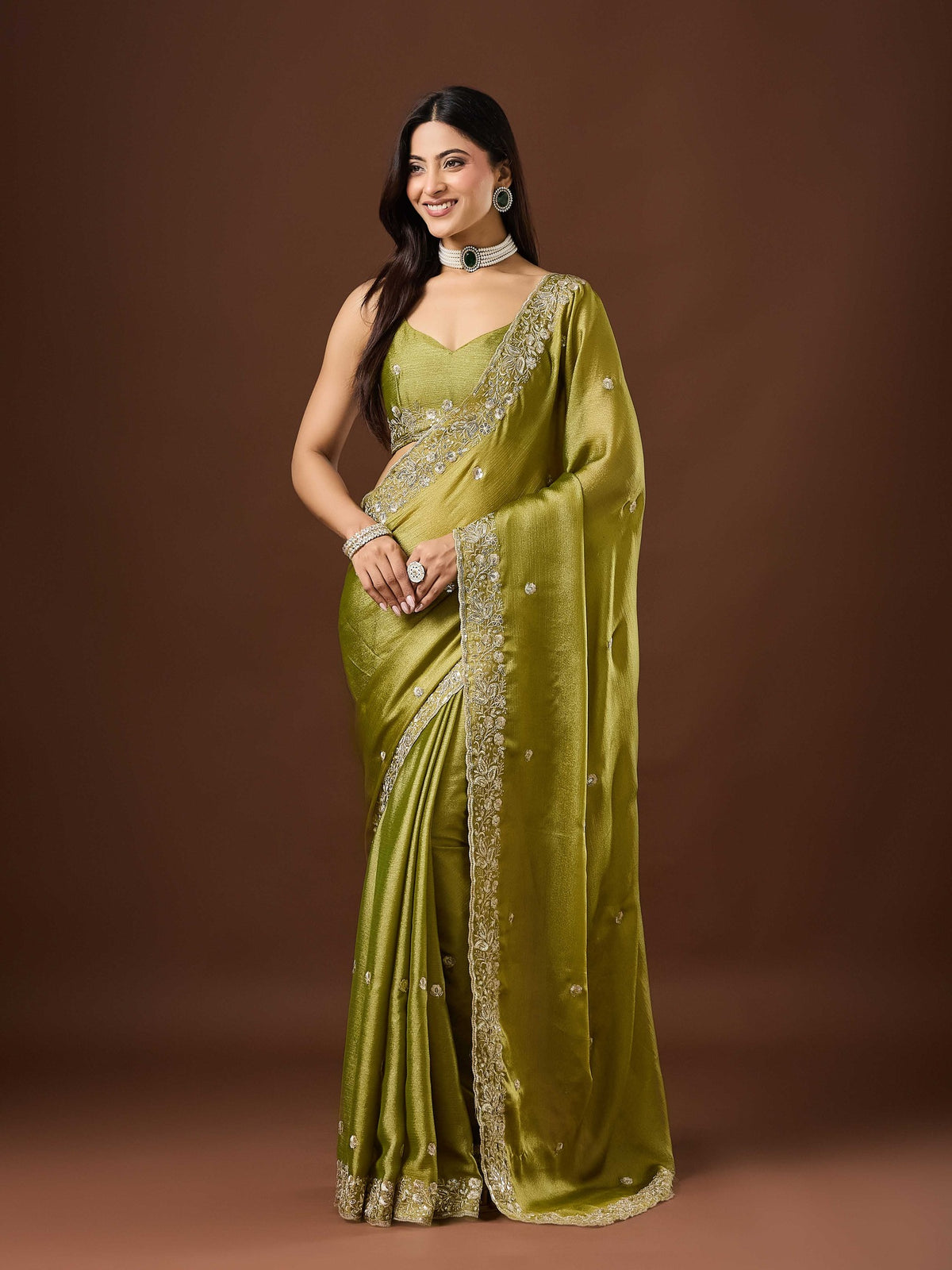 Woman wearing olive chinnon saree with embroidered motif work and olive blouse