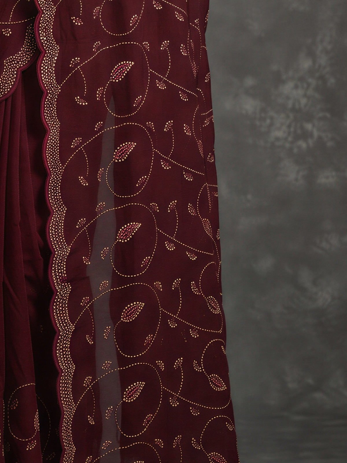 Pallu detail of wine satin saree showing ornamented surface design and embellished border