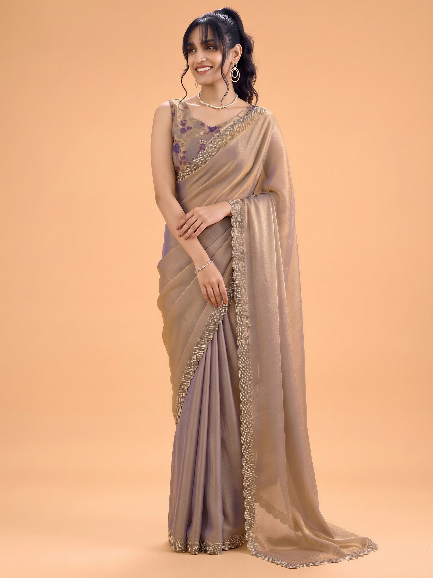 Woman wearing metallic silk saree with ornamented surface design and metallic blouse