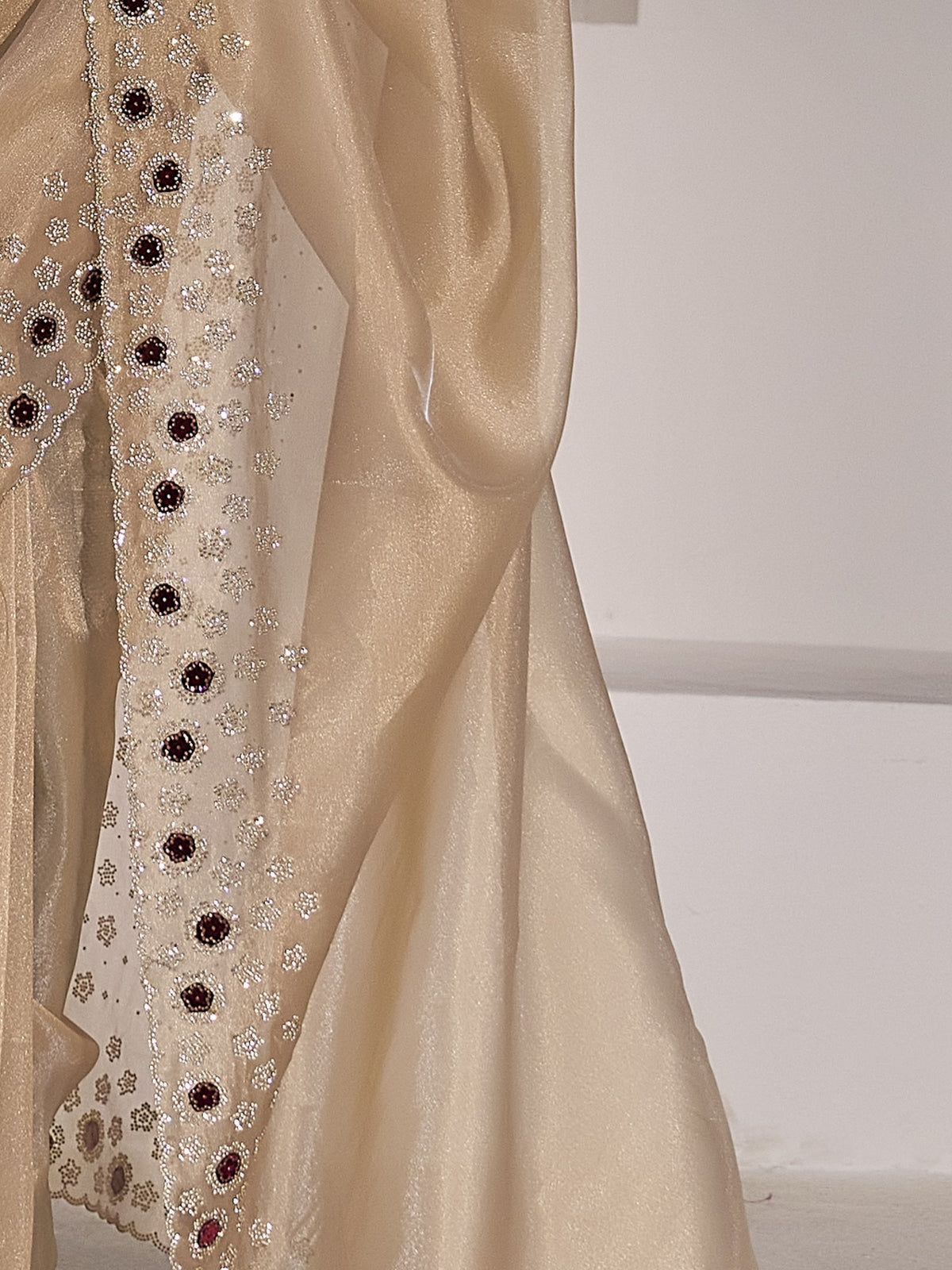 Pallu detail of champagne organza saree showing applique design and scallop border