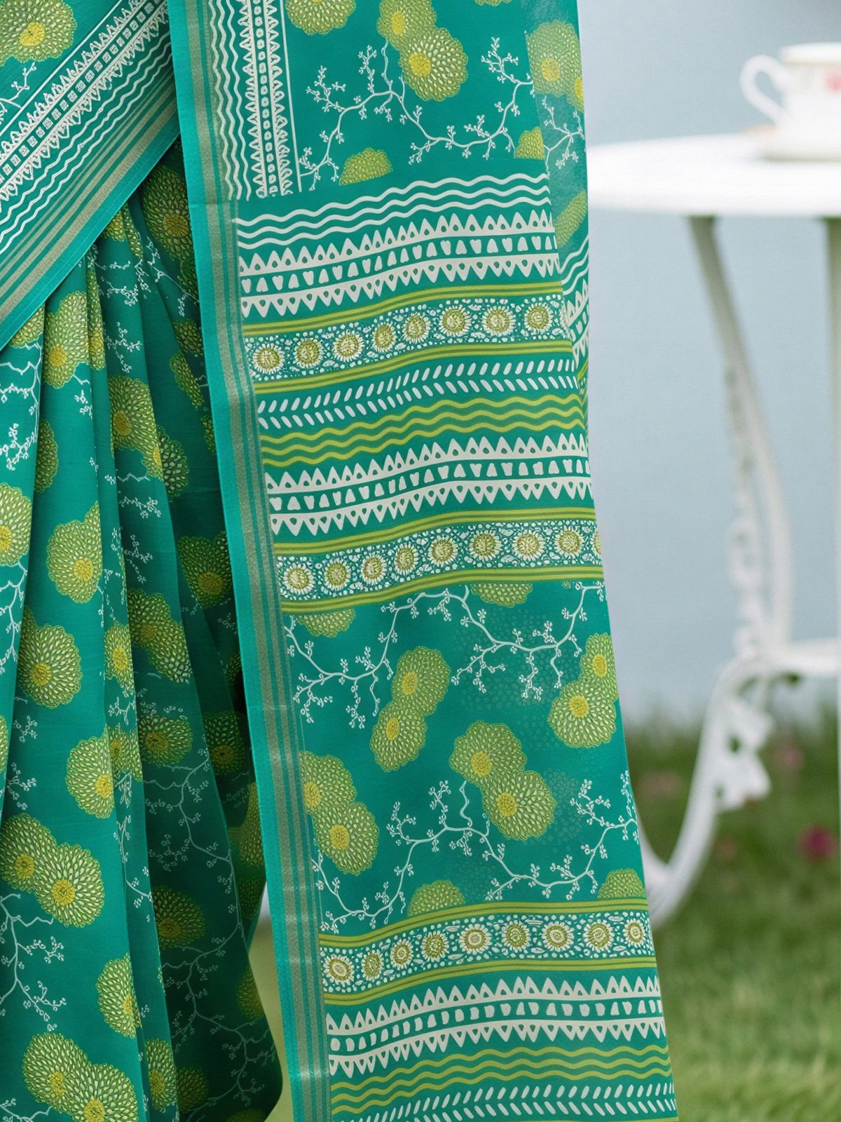 Pallu detail of teal green crepe saree showing botanical floral and leaf design and zari border