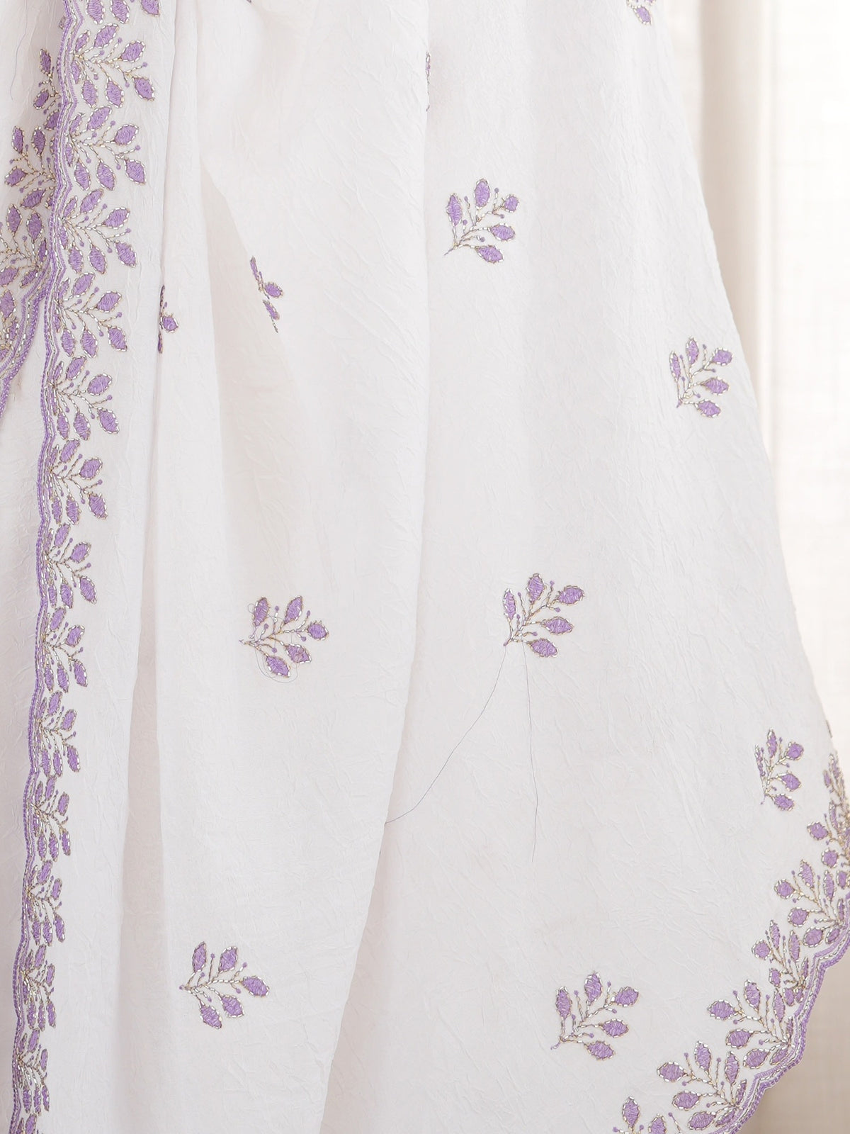 Pallu detail of white poly georgette saree showing ornamented surface design and embellished border