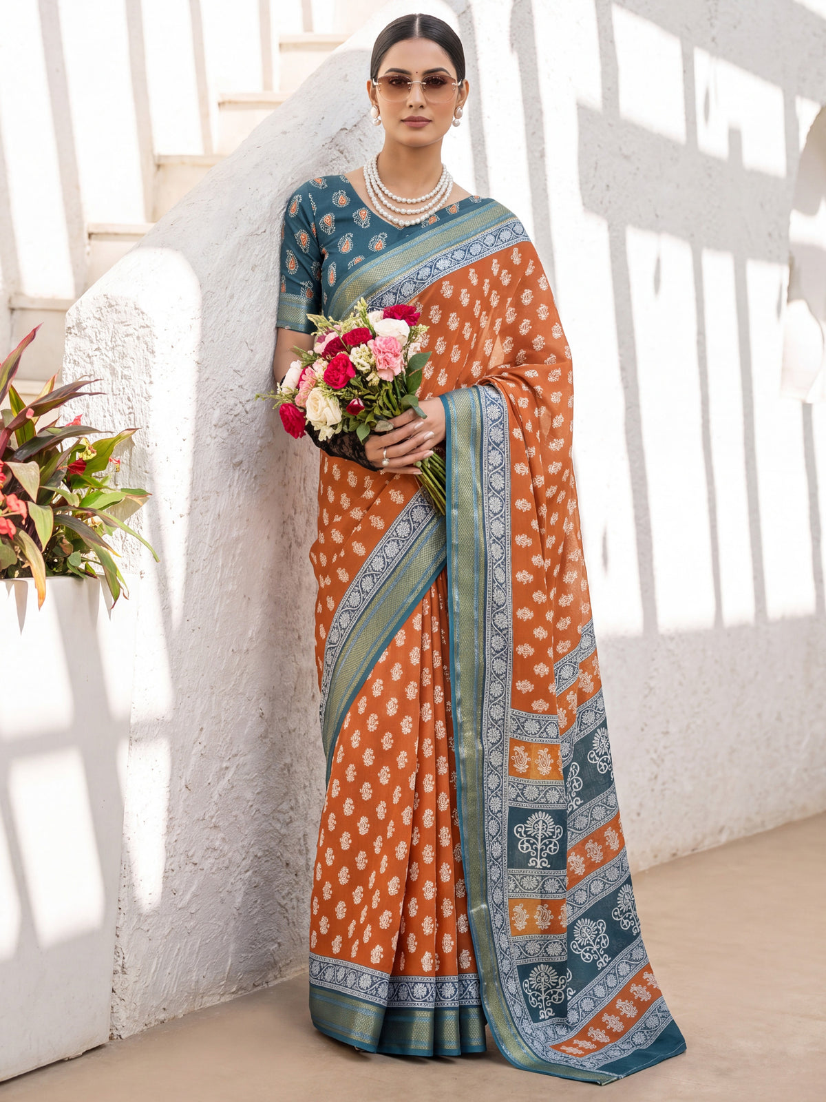 Woman wearing rust cotton saree with traditional indian motif work and teal blue blouse