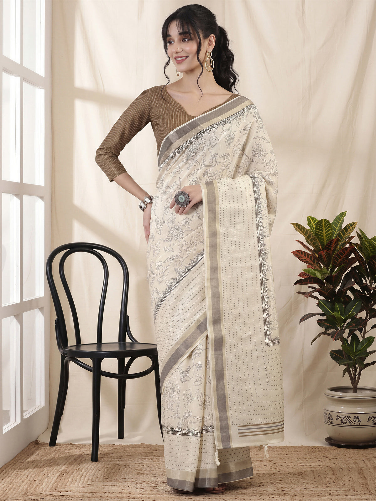 Woman wearing off white cotton silk saree with ornamented surface design and beige blouse
