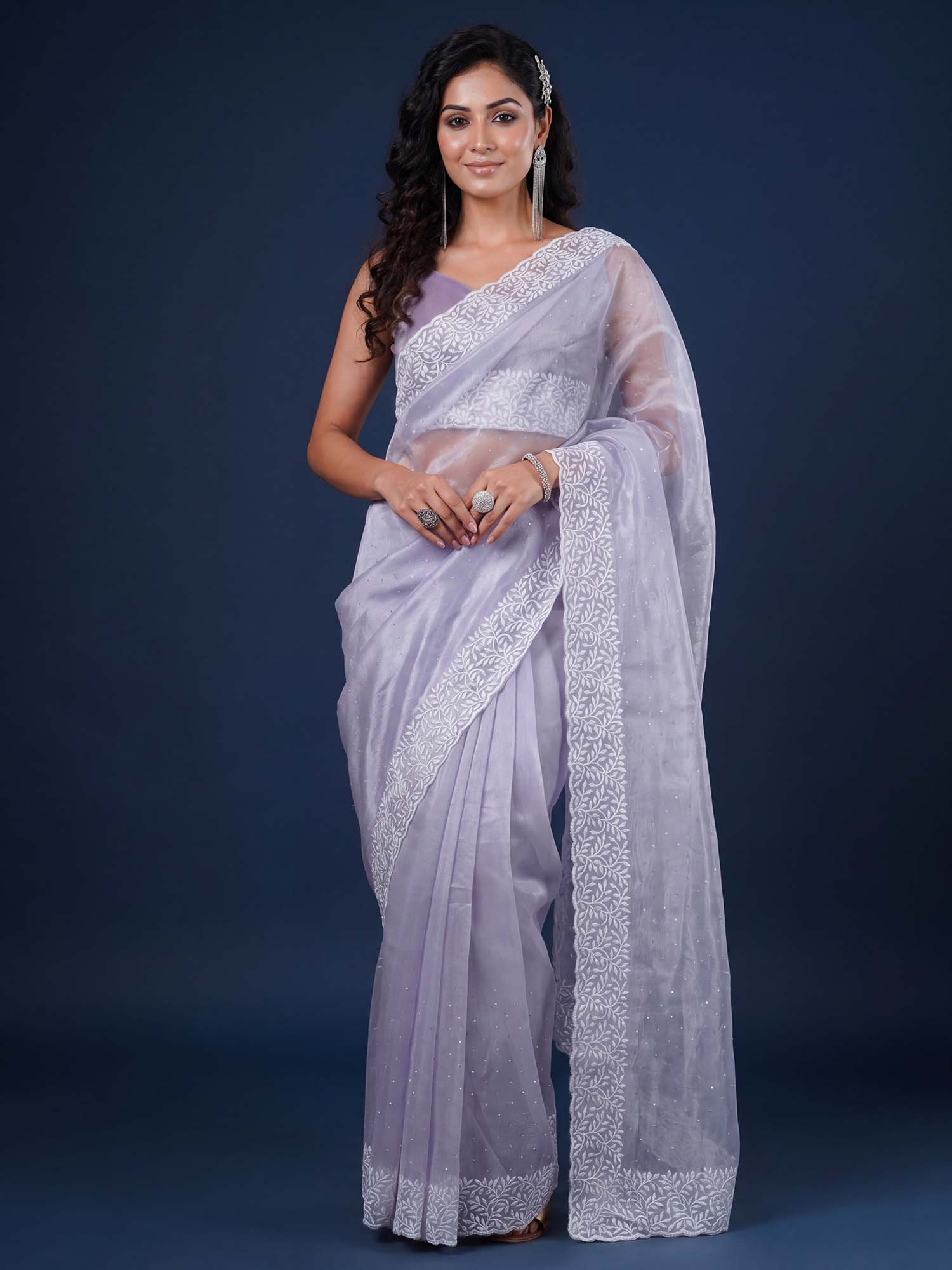 Woman wearing lavender organza saree with ornamented surface design and lavender blouse