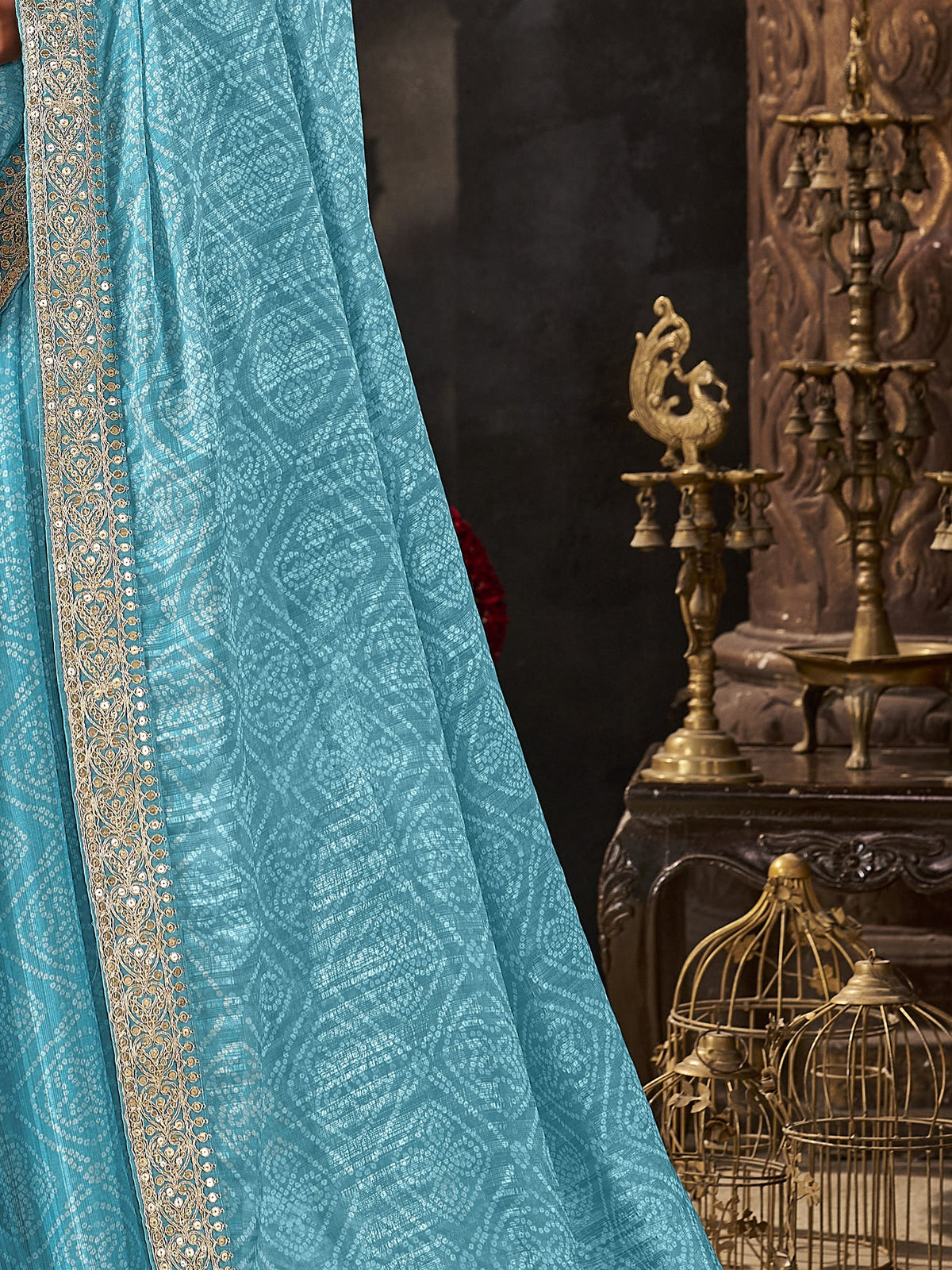 Pallu detail of turquoise blue chiffon saree showing bandhani tie-dye dot work and embellished border