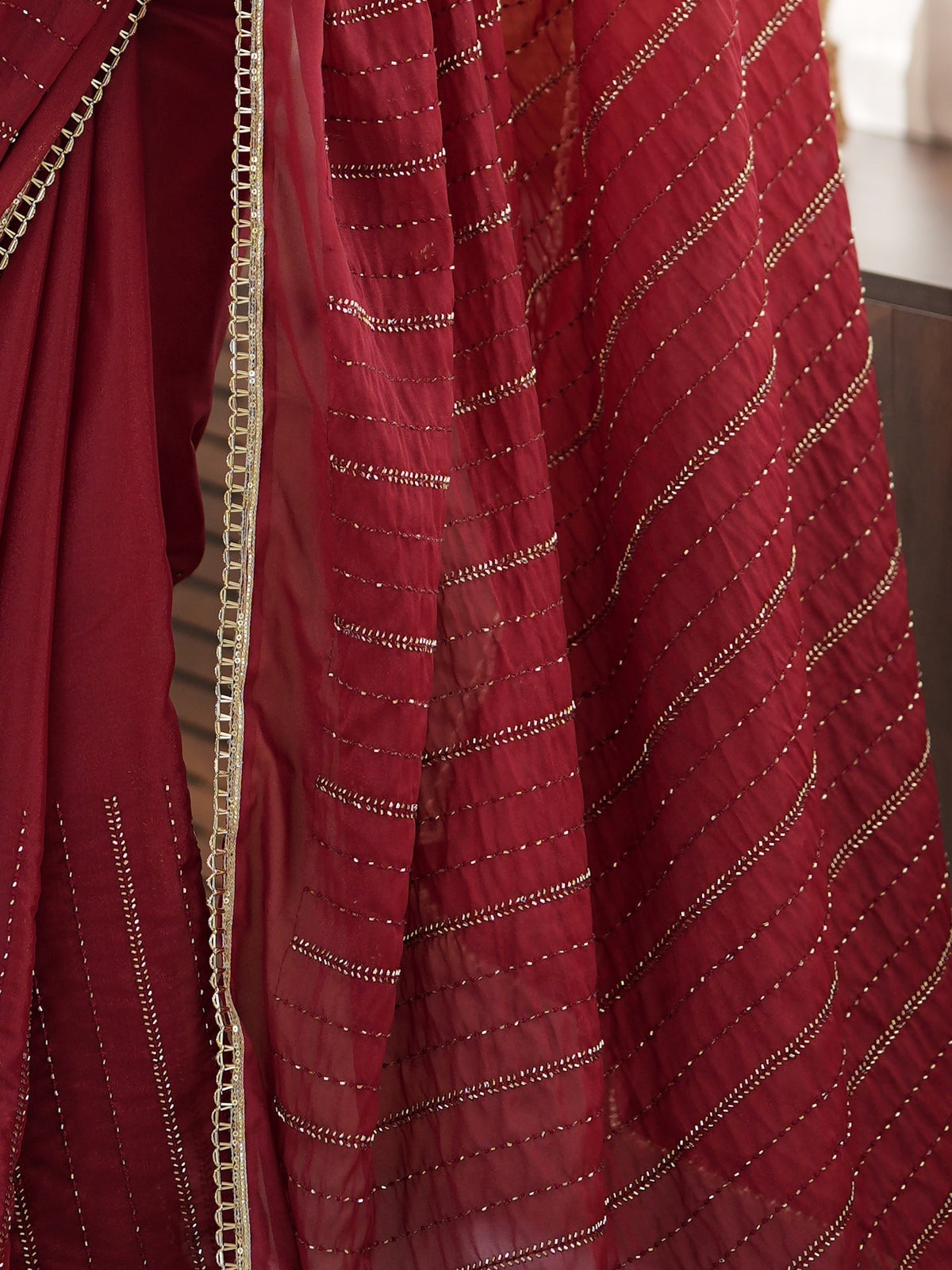 Pallu detail of maroon georgette saree showing ornamented surface design and embellished border