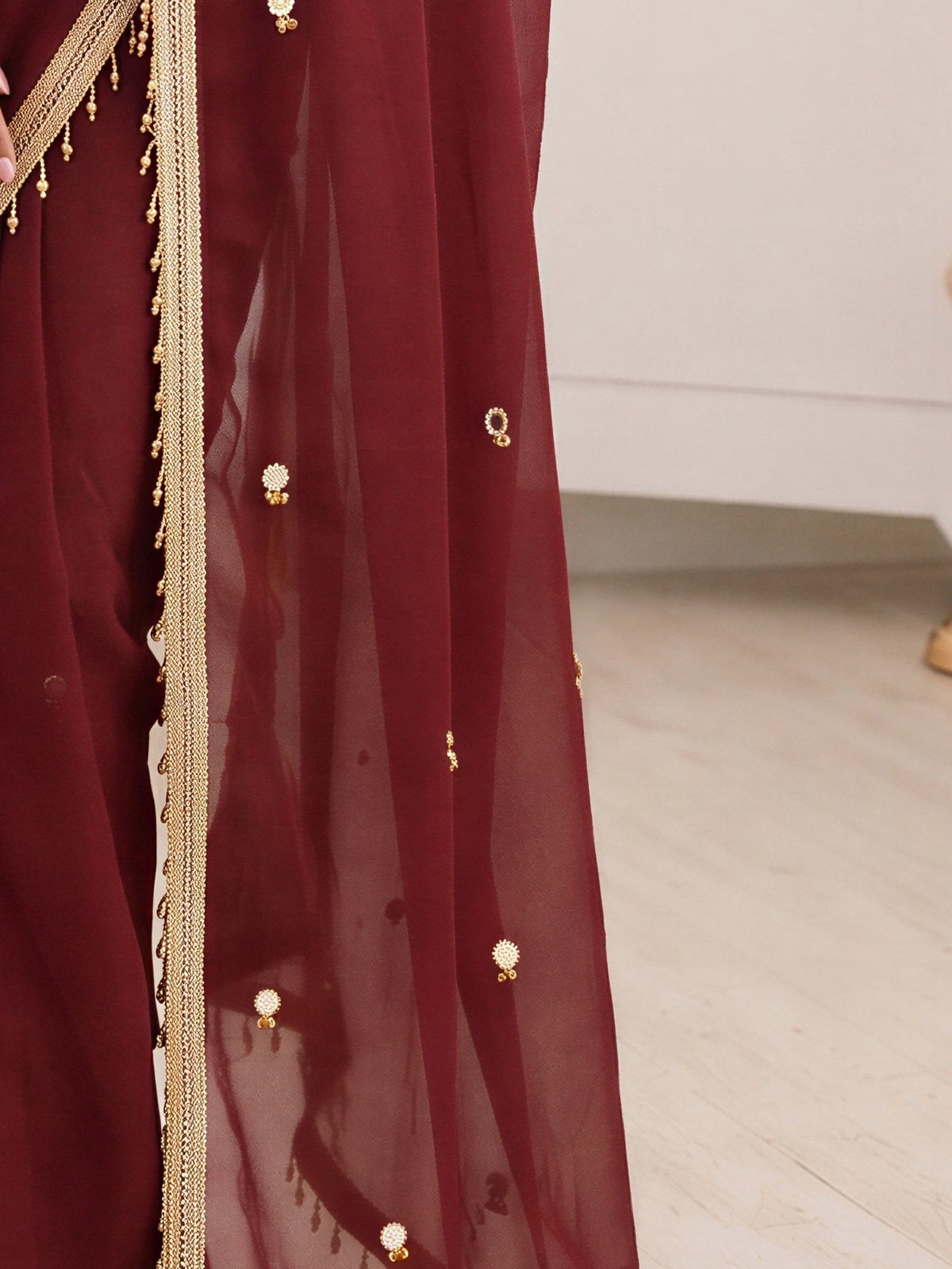 Pallu detail of maroon poly georgette saree showing ornamented surface design and embellished border