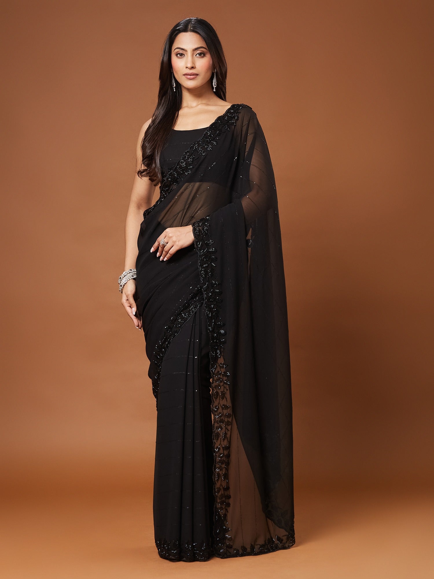 Woman wearing black georgette saree with ornamented surface design and black blouse
