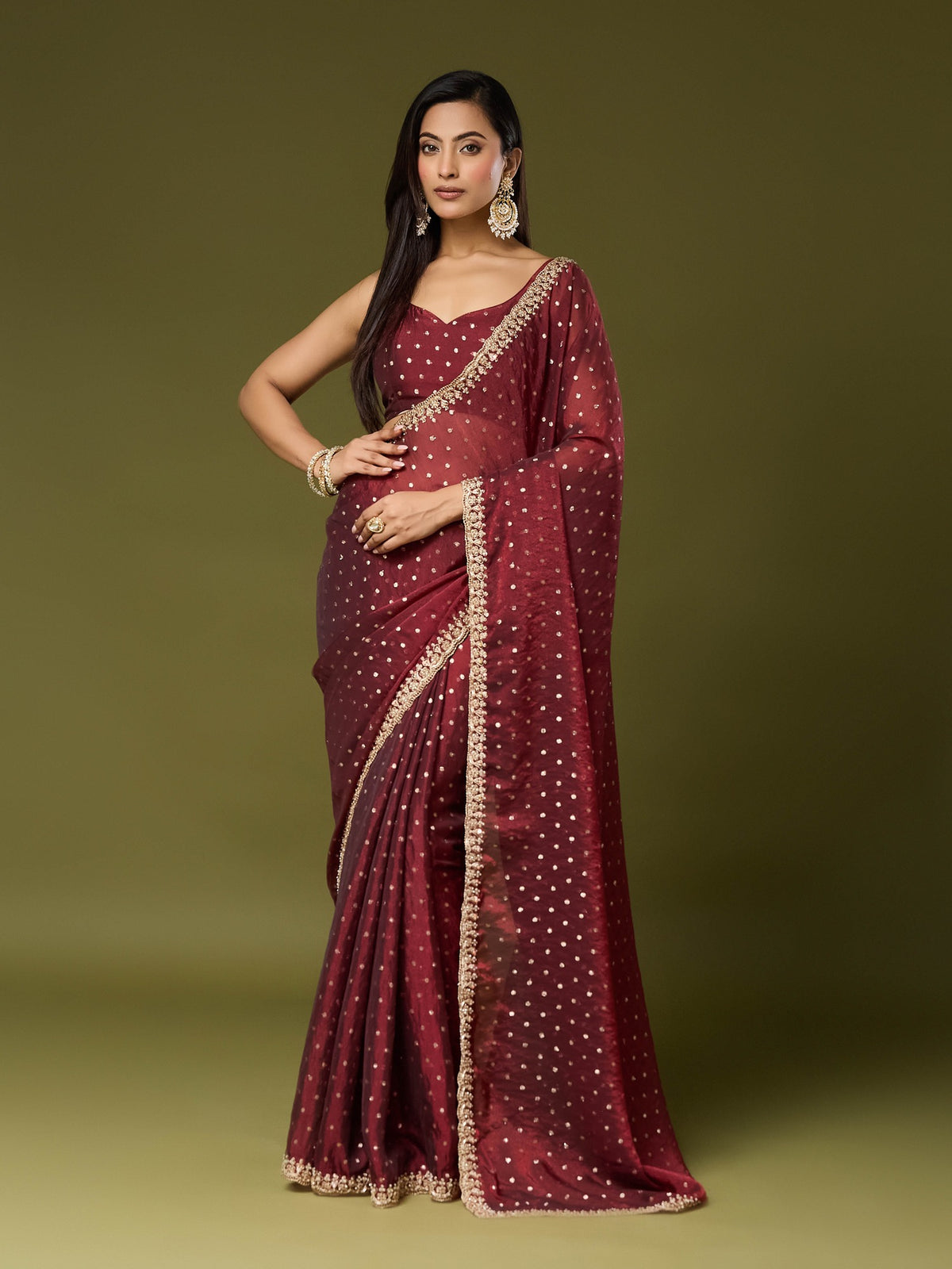 Woman wearing maroon georgette saree with ornamented surface design and maroon blouse