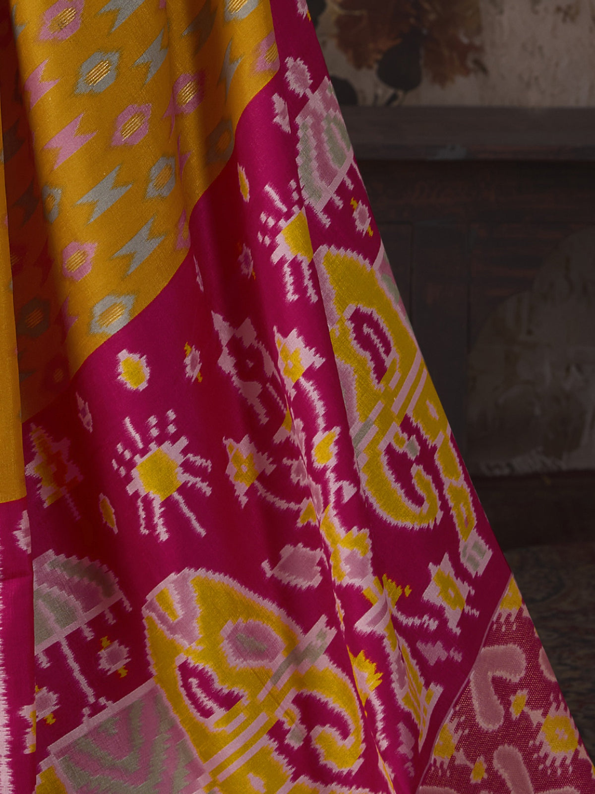 Pallu detail of mustard silk blend saree showing ikat resist-dyed pattern and embellished border