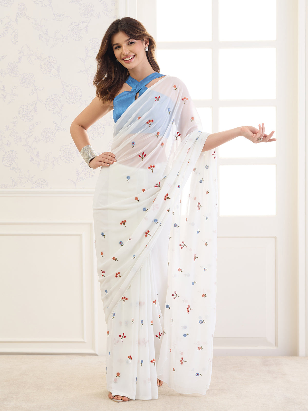 Woman wearing white georgette saree with all-over floral design and light blue blouse