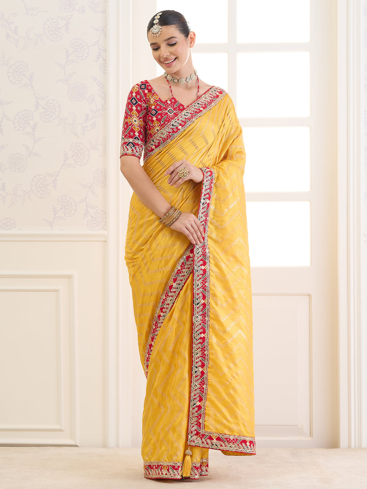 Woman wearing yellow dola silk saree with metallic foil print work and red blouse