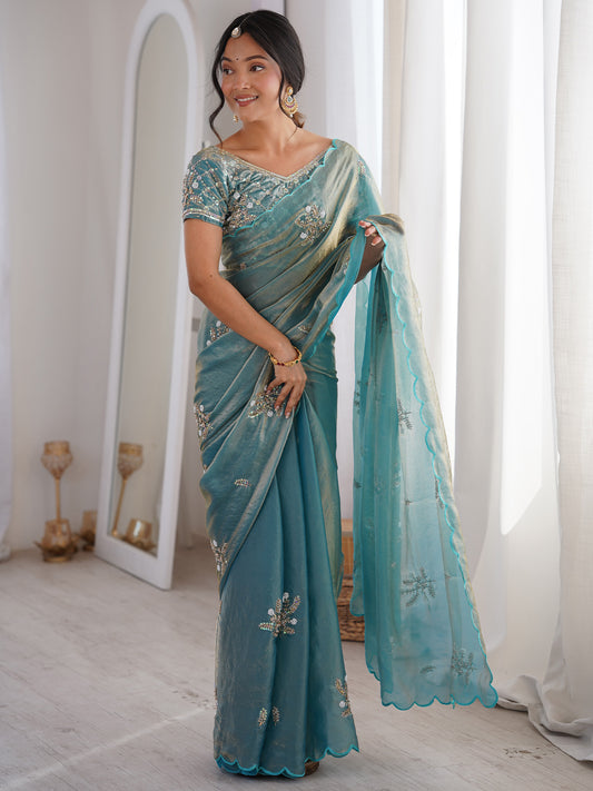 Woman wearing light blue satin saree with ornamented surface design and light blue blouse