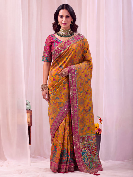 Woman wearing mustard silk blend saree with traditional indian motif work and pink blouse