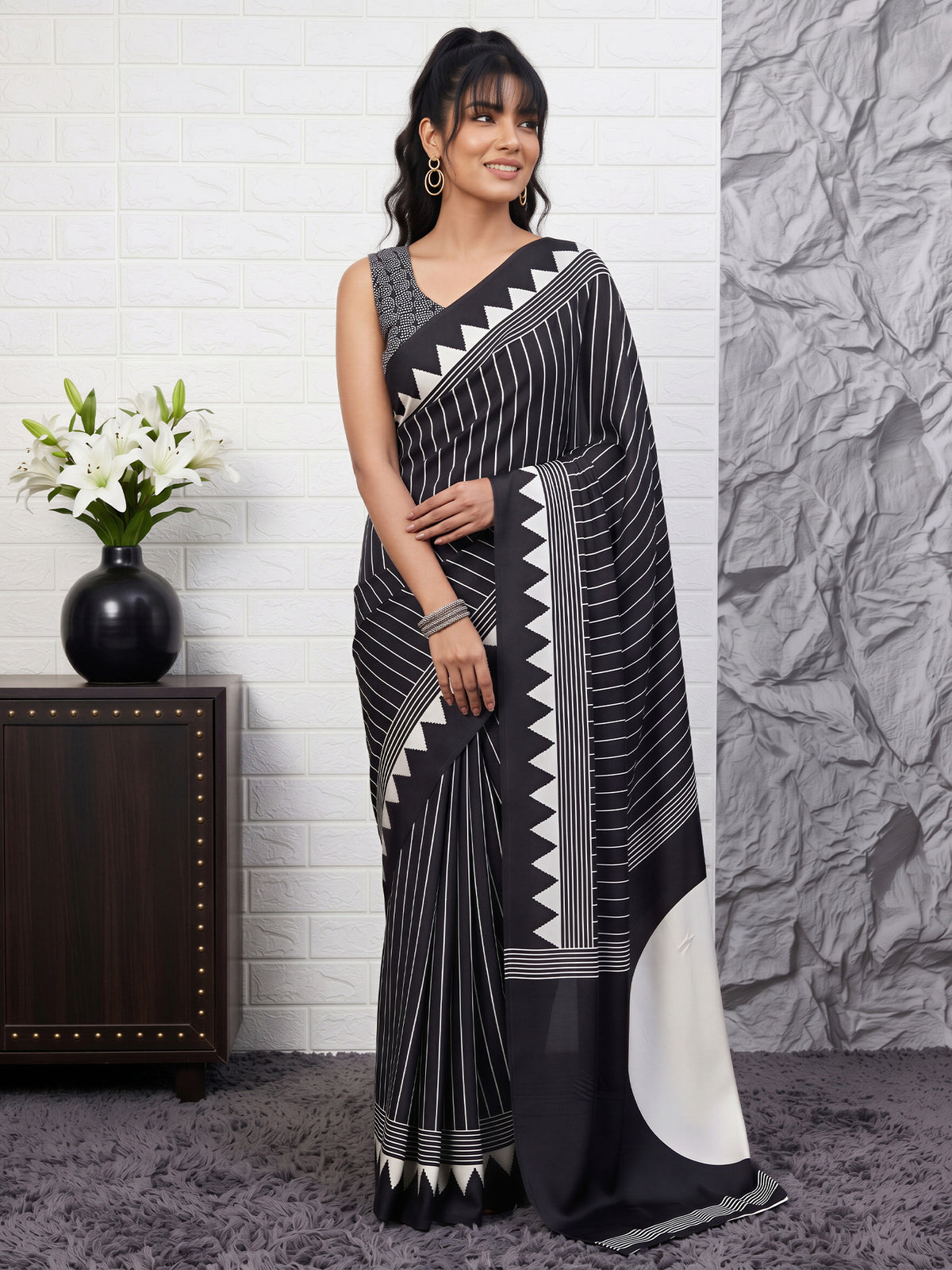 Woman wearing black satin saree with striped pattern design and black blouse