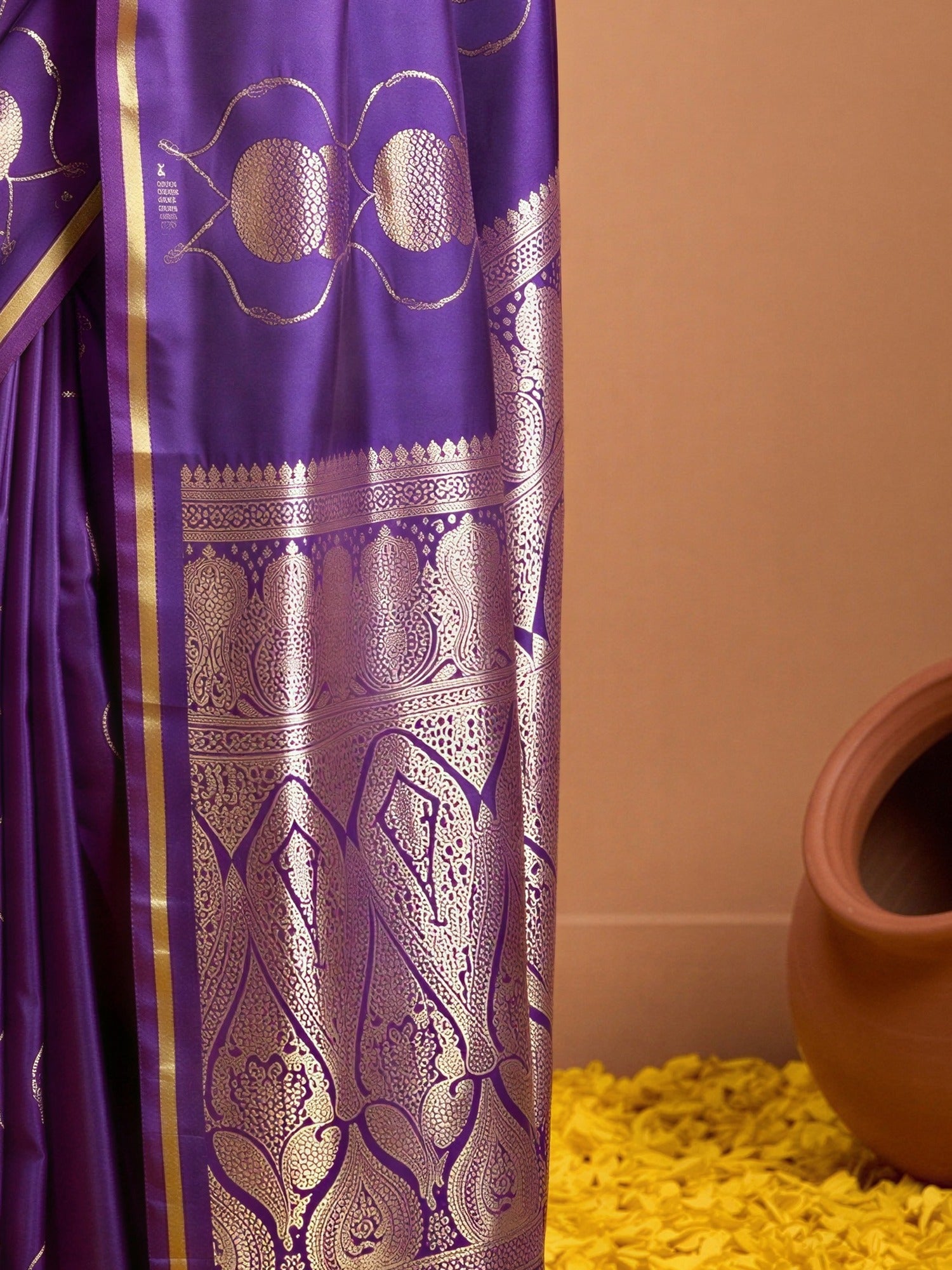 Pallu detail of purple satin saree showing zari butta (metallic motif) work and zari border