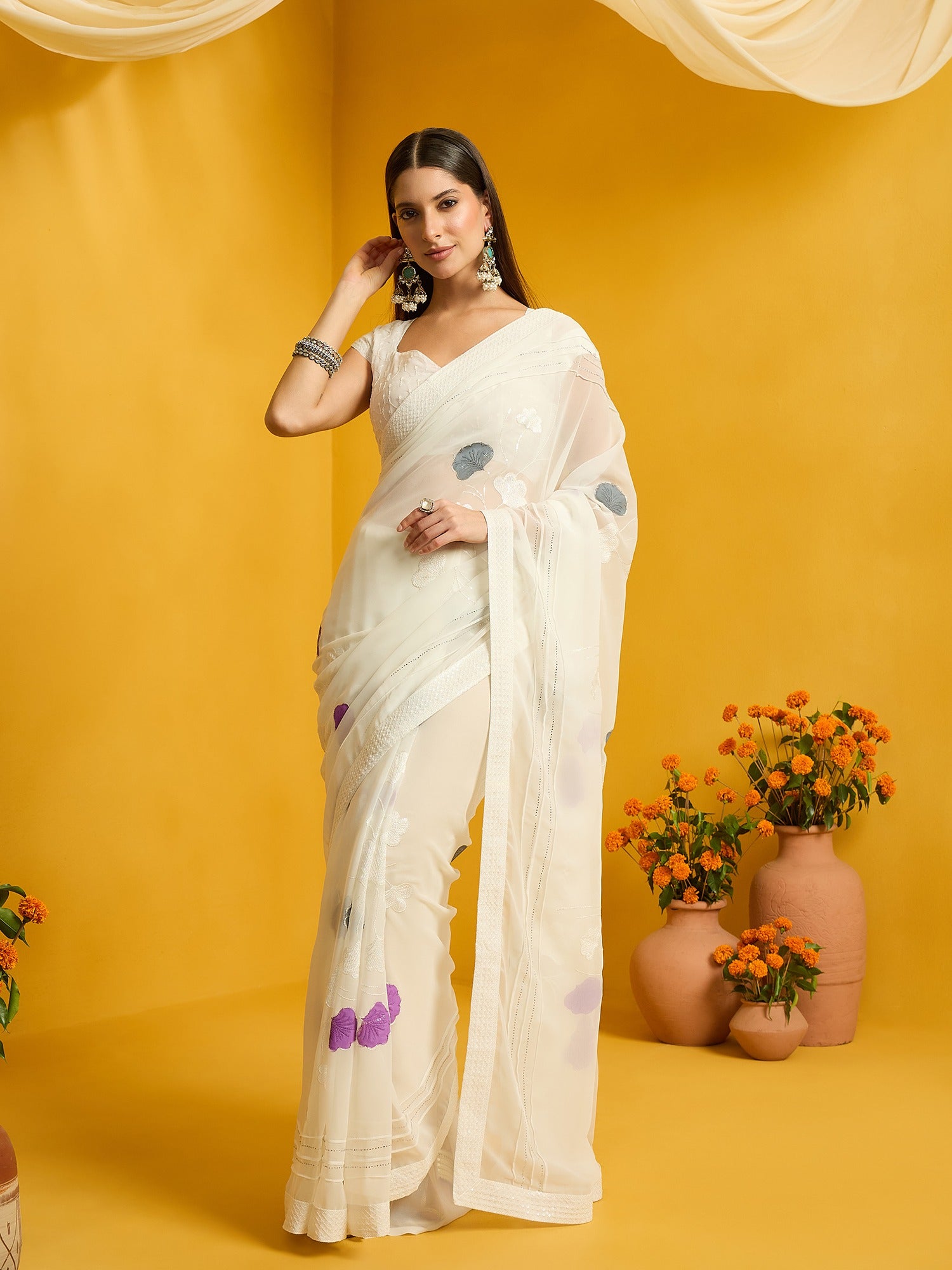Woman wearing off white georgette saree with embroidered motif work and off white blouse