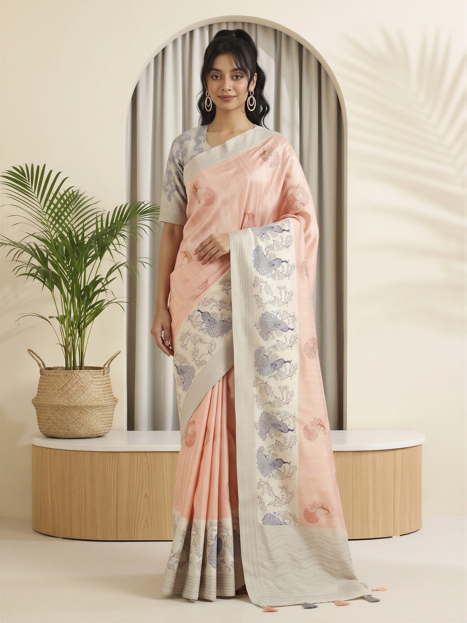 Woman wearing peach silk blend saree with peacock motif design and grey blouse