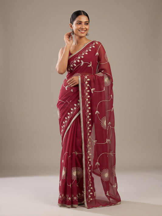 Woman wearing pink georgette saree with embroidered motif work and magenta blouse