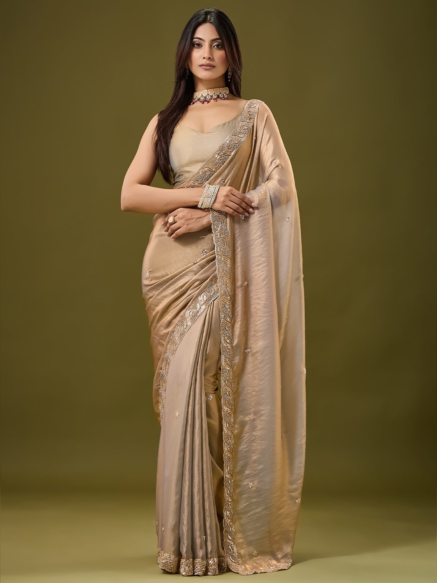 Woman wearing metallic satin saree with ornamented surface design and metallic blouse