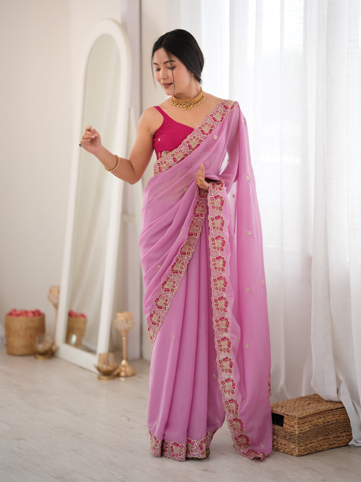Woman wearing pink georgette saree with ornamented surface design and pink blouse