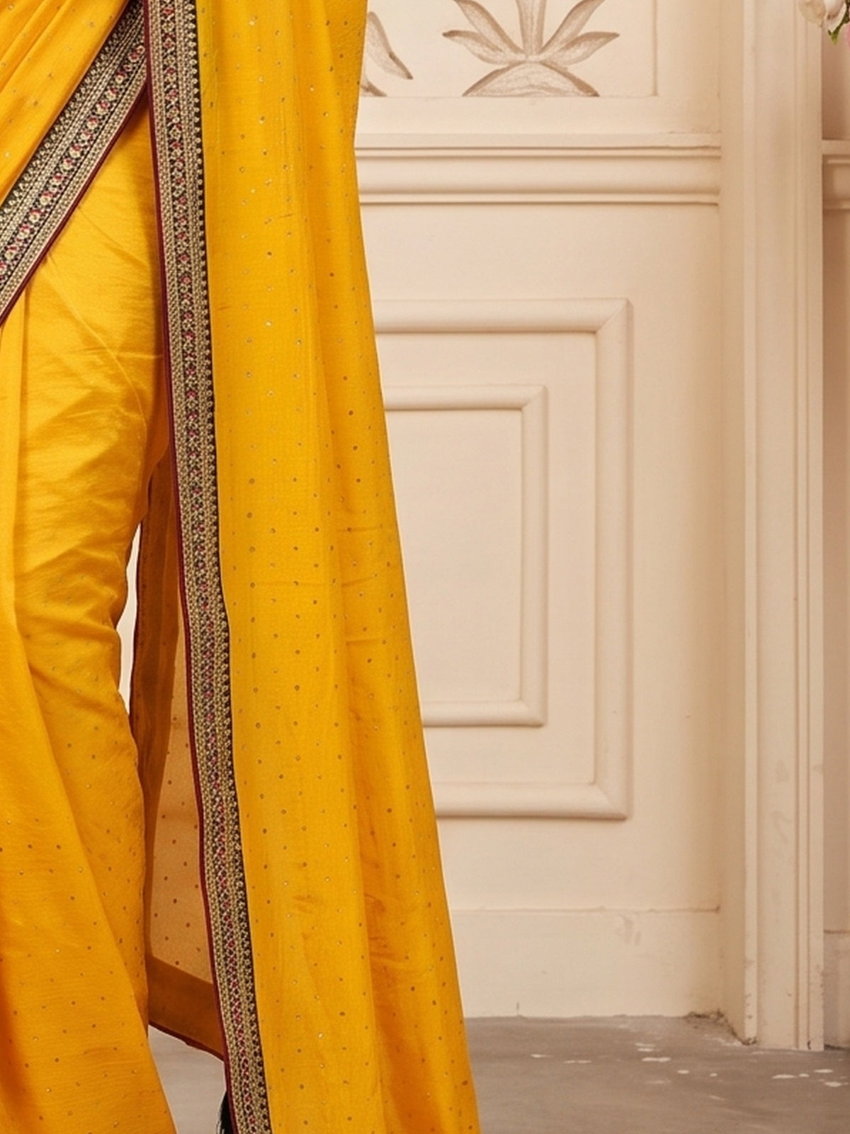 Pallu detail of mustard vichitra silk saree showing ornamented surface design and embellished border