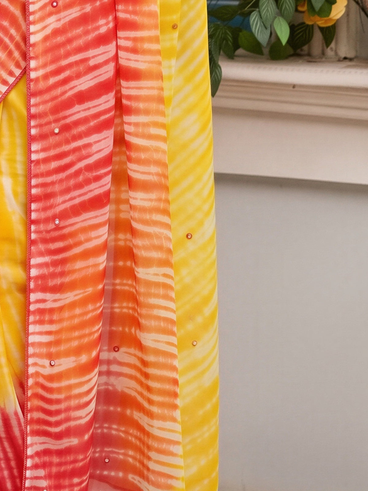 Pallu detail of yellow georgette saree showing leheriya design and embroidered border