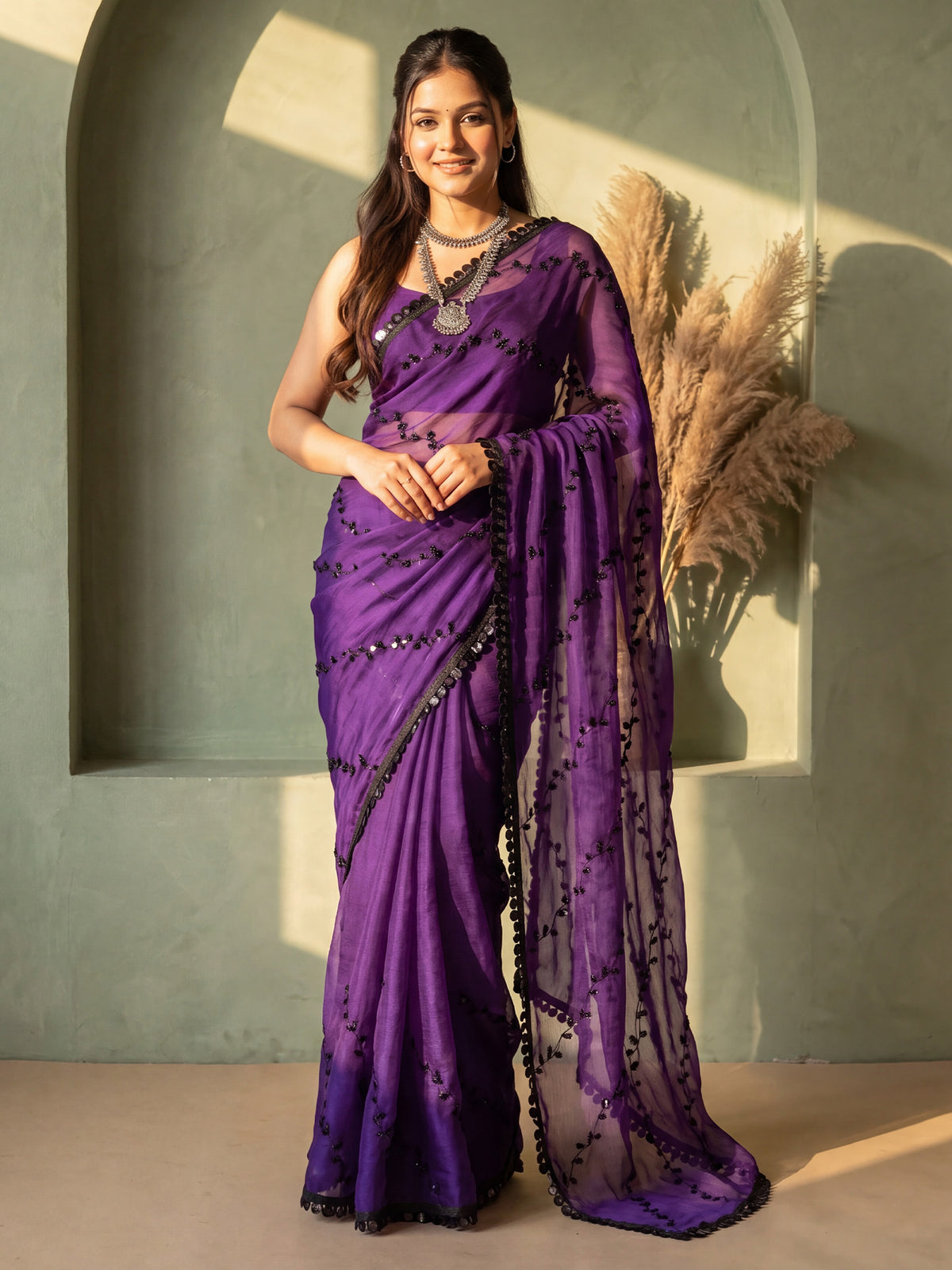 Woman wearing purple chiffon saree with ornamented surface design and purple blouse