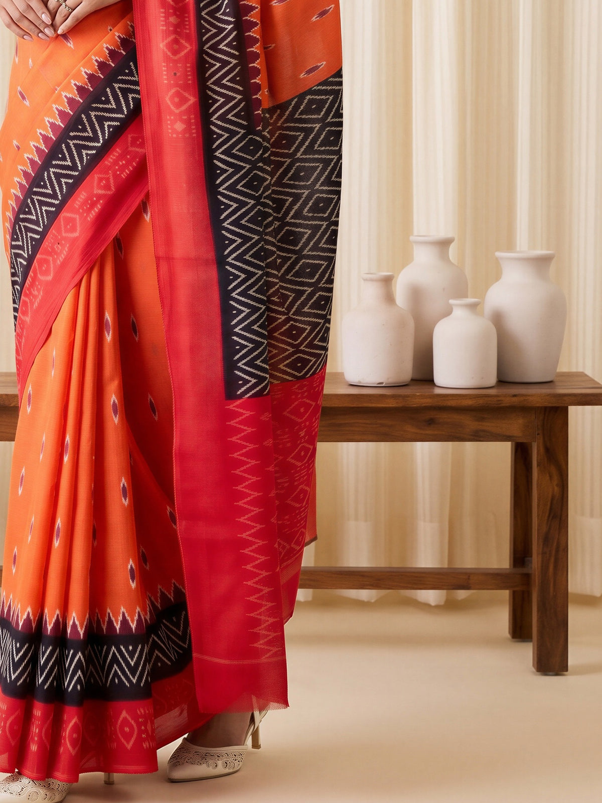 Pallu detail of orange cotton blend saree showing ikat resist-dyed pattern and printed border