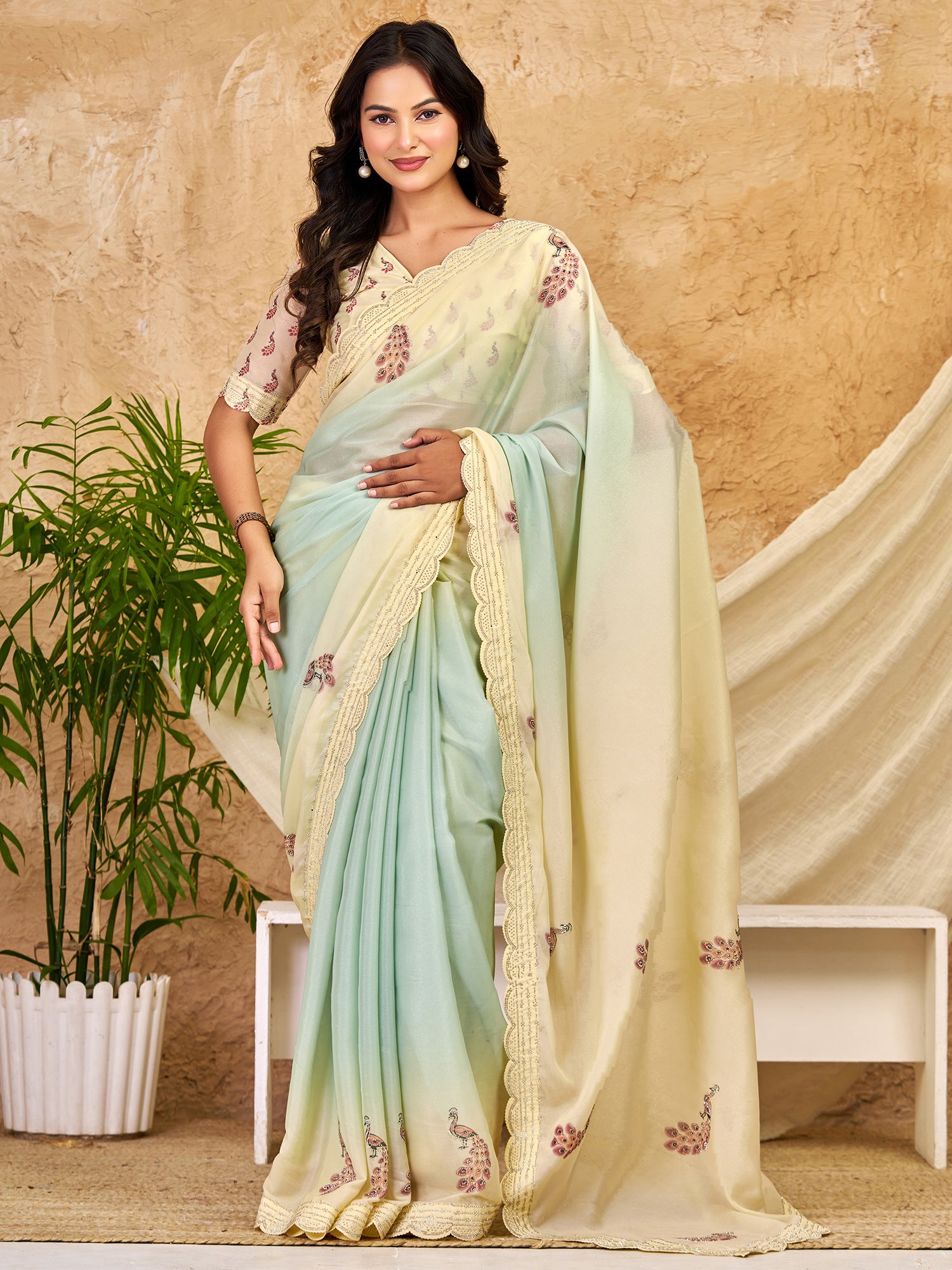 Woman wearing mint green georgette saree with peacock motif design and mint green blouse