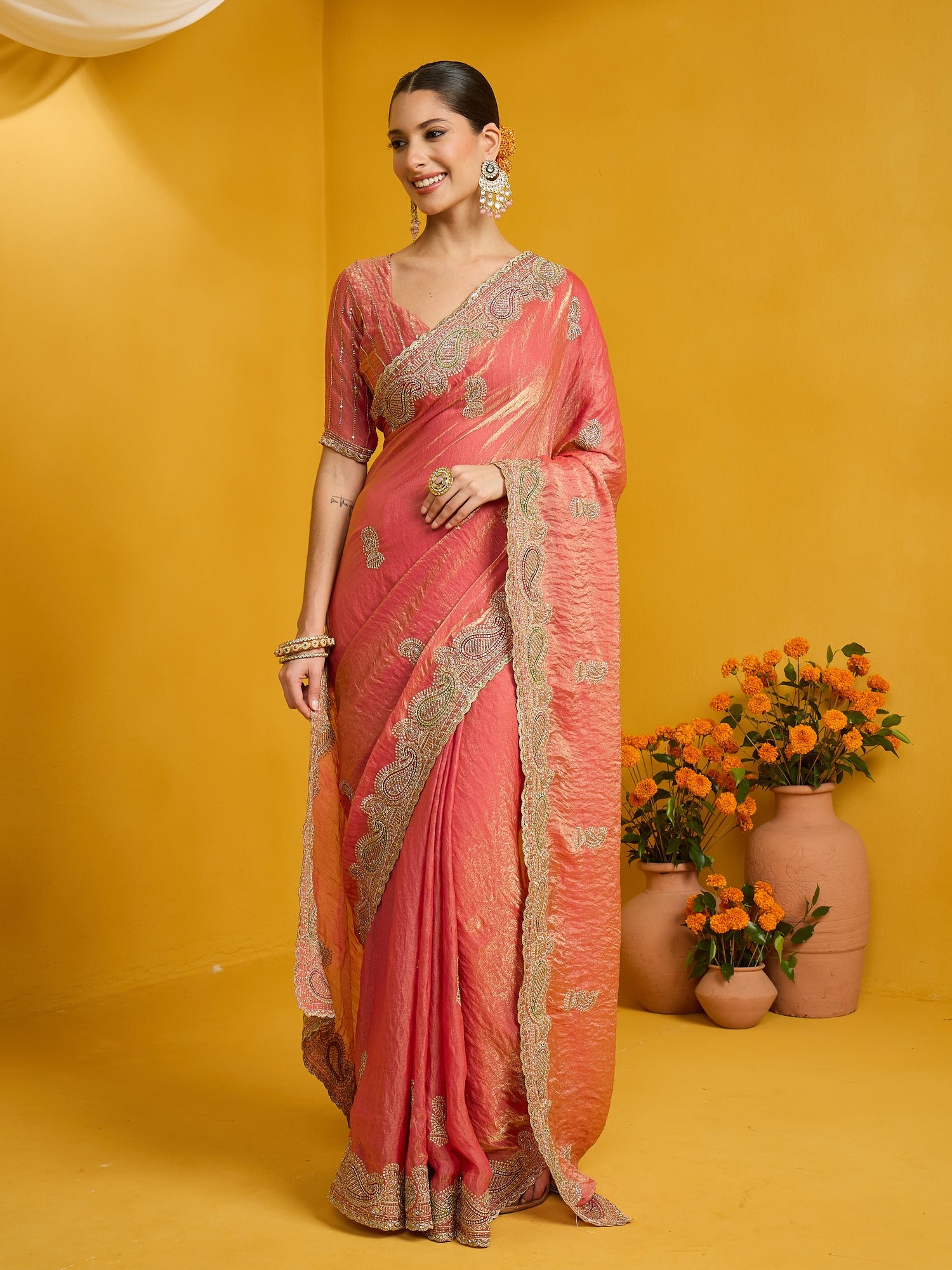Woman wearing peach satin silk saree with zari butta (metallic motif) work and peach blouse