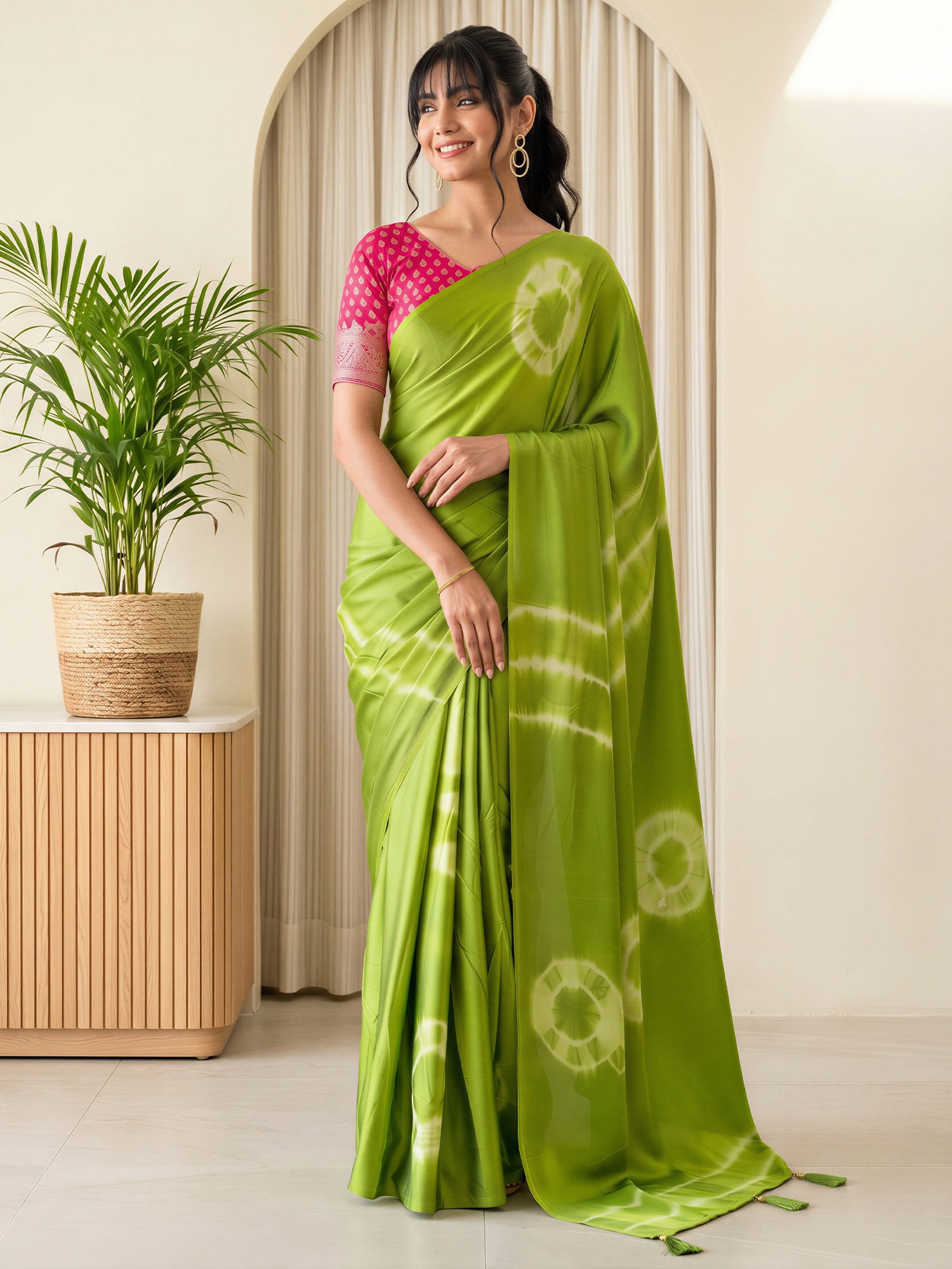 Woman wearing light green satin silk saree with tie-and-dye resist pattern and pink blouse