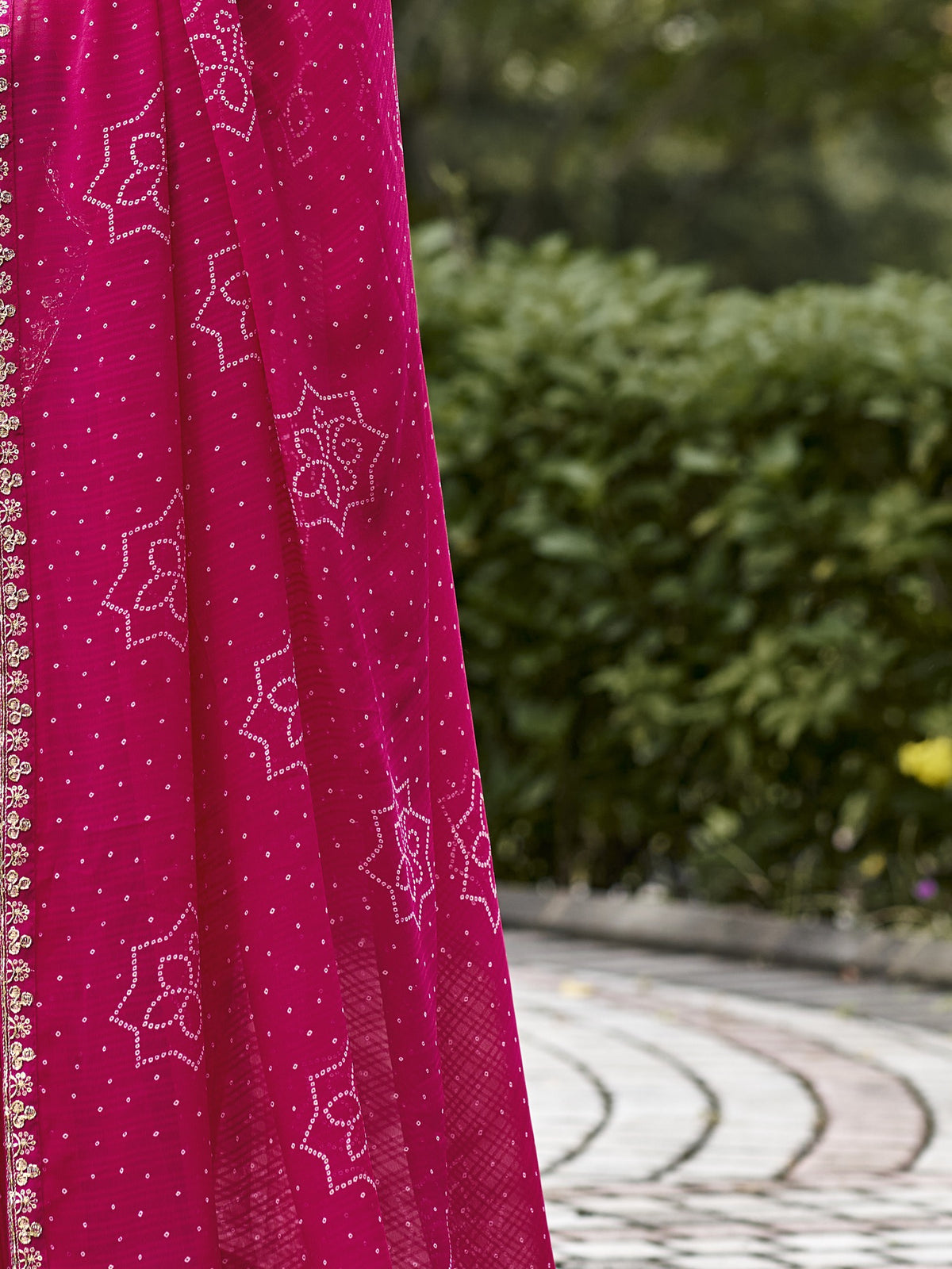 Pallu detail of pink georgette saree showing bandhani tie-dye dot work and zari border