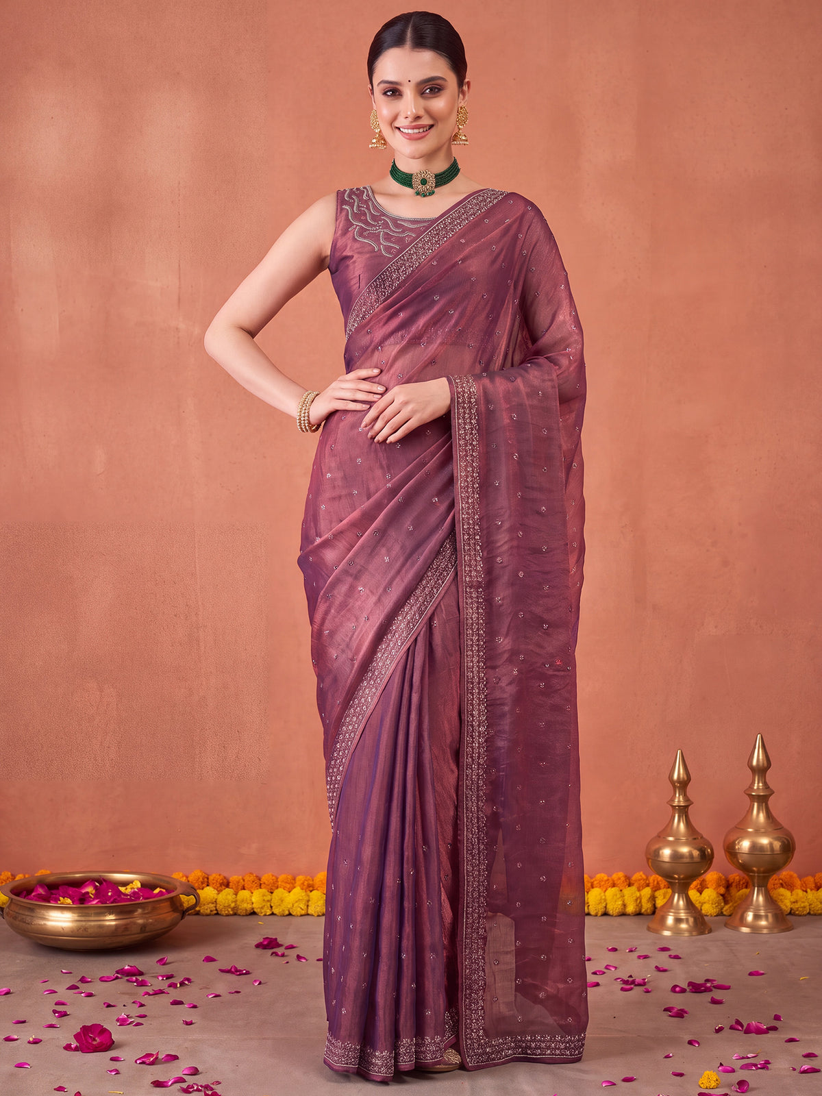 Woman wearing mauve satin silk saree with ornamented surface design and mauve blouse
