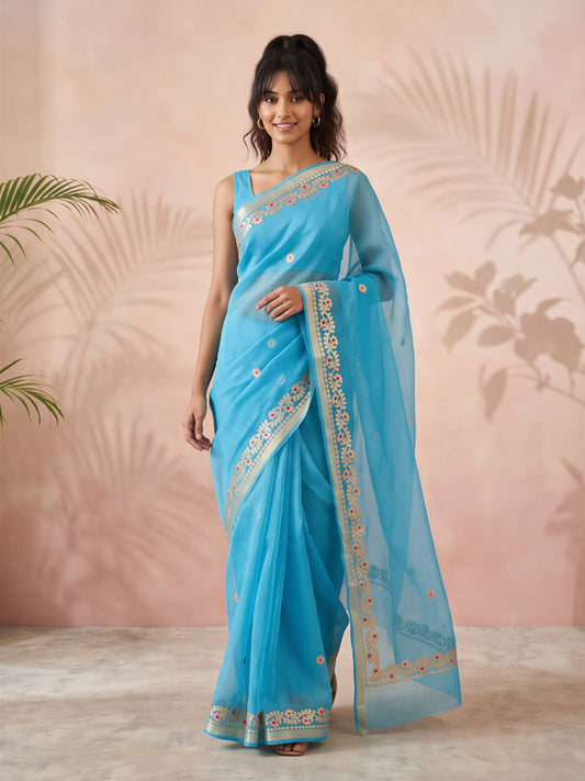 Woman wearing turquoise blue kota doria cotton saree with ornamented surface design and turquoise blue blouse