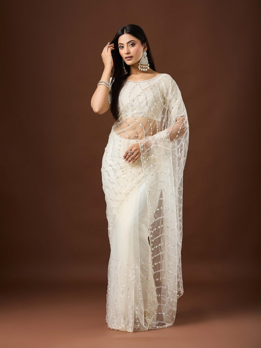 Woman wearing white net saree with ornamented surface design and white blouse