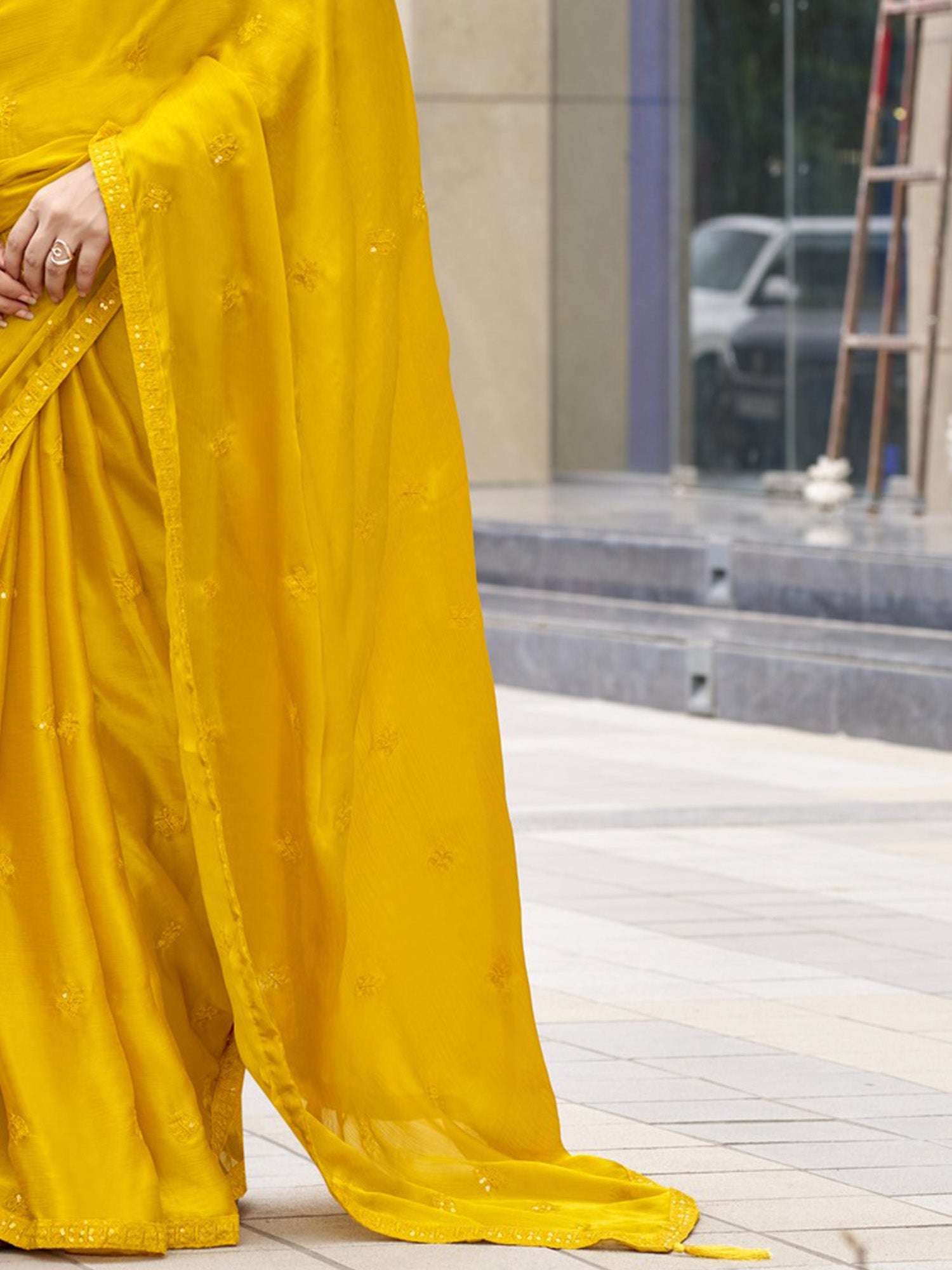 Pallu detail of yellow satin silk saree showing ornamented surface design and embellished border