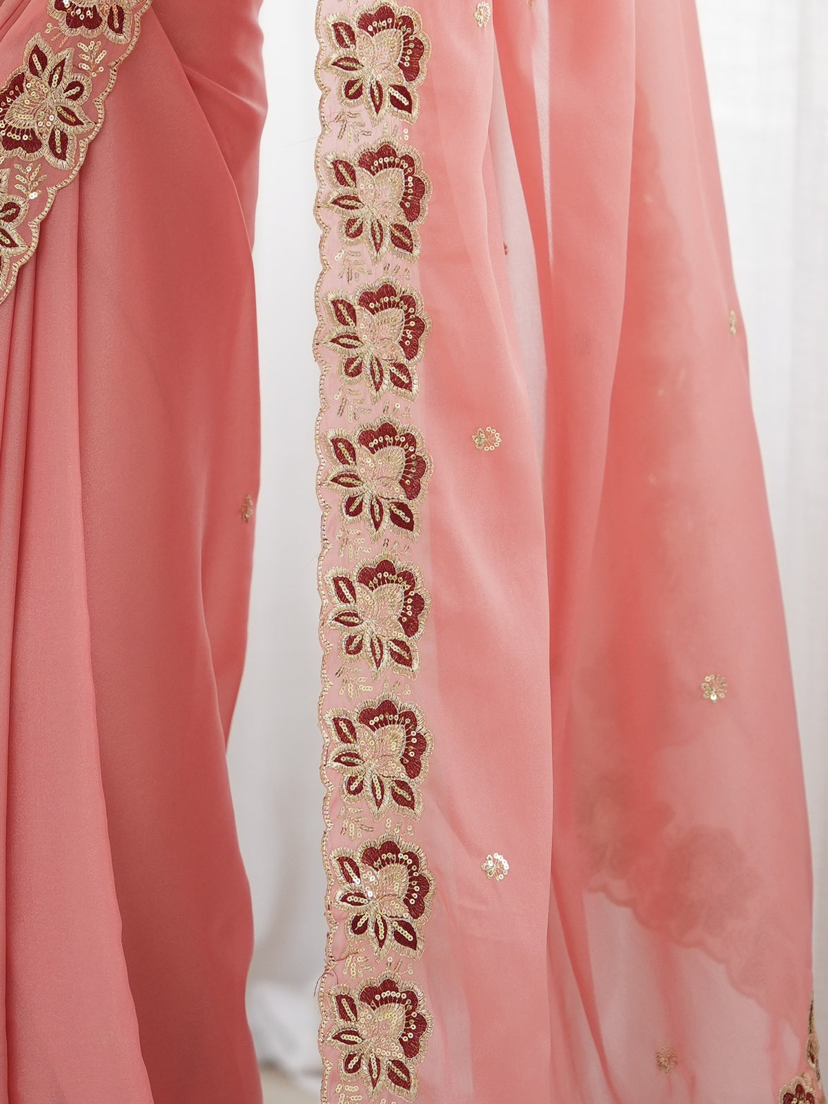 Pallu detail of peach georgette saree showing ornamented surface design and embellished border