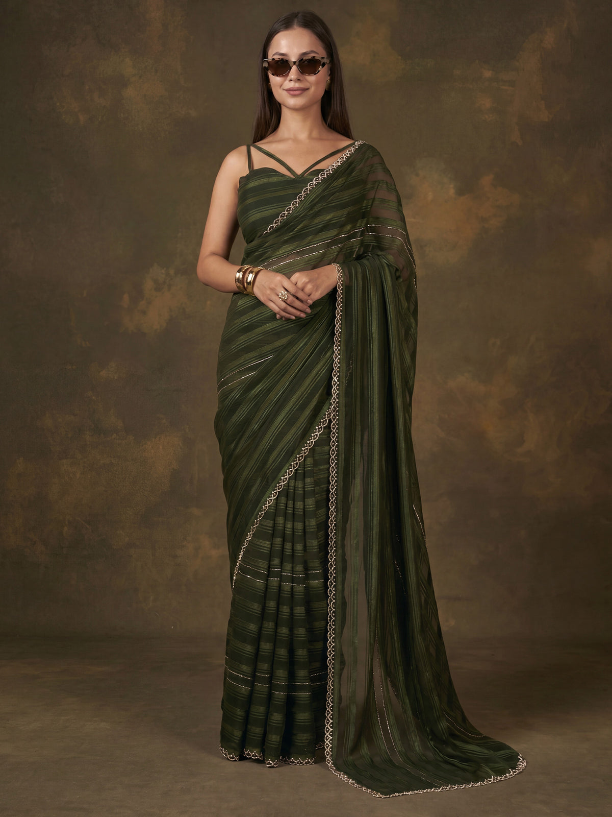 Woman wearing dark green georgette saree with striped pattern design and dark green blouse