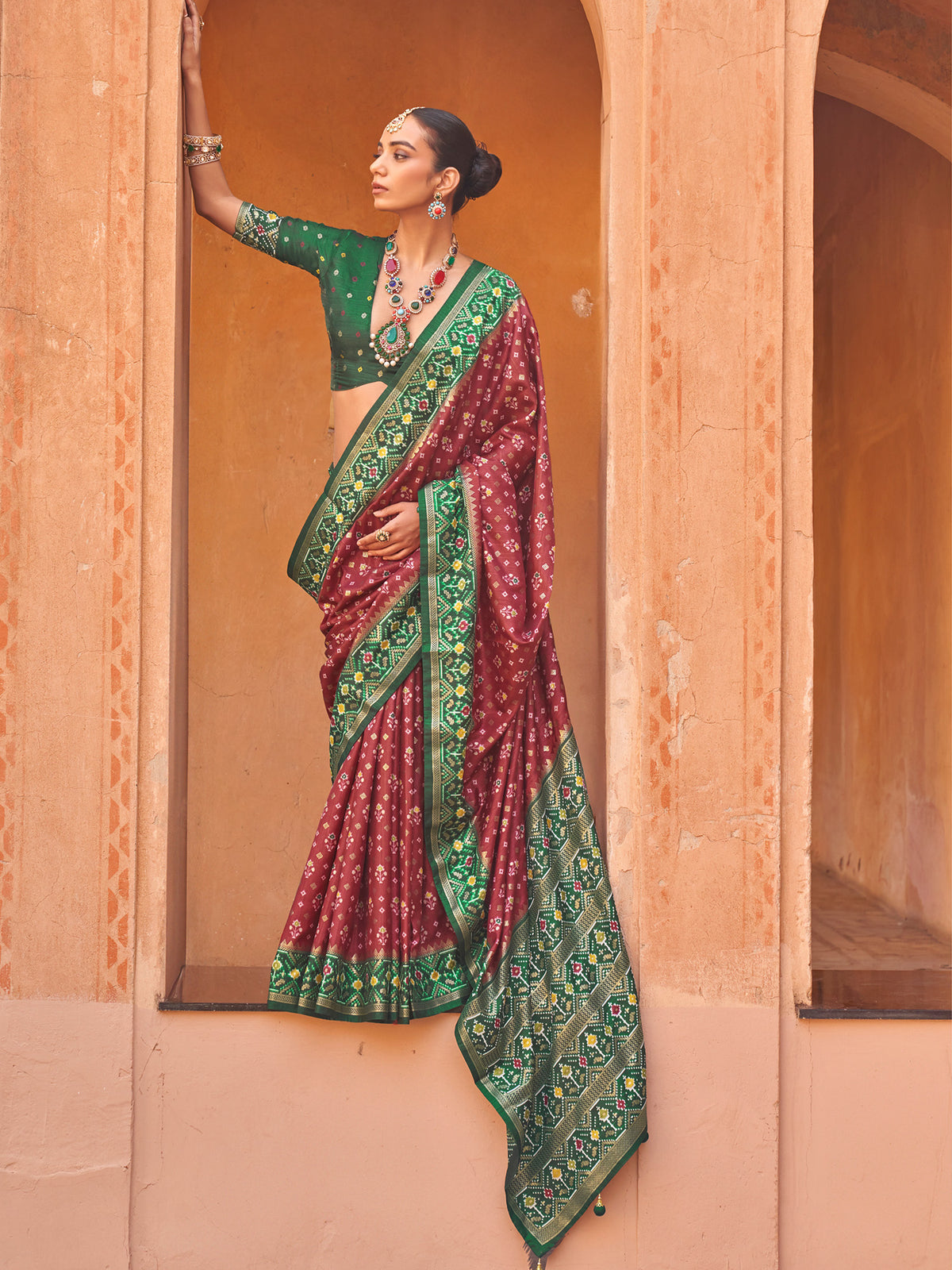 Woman wearing burgundy silk blend saree with ikat resist-dyed pattern and green blouse