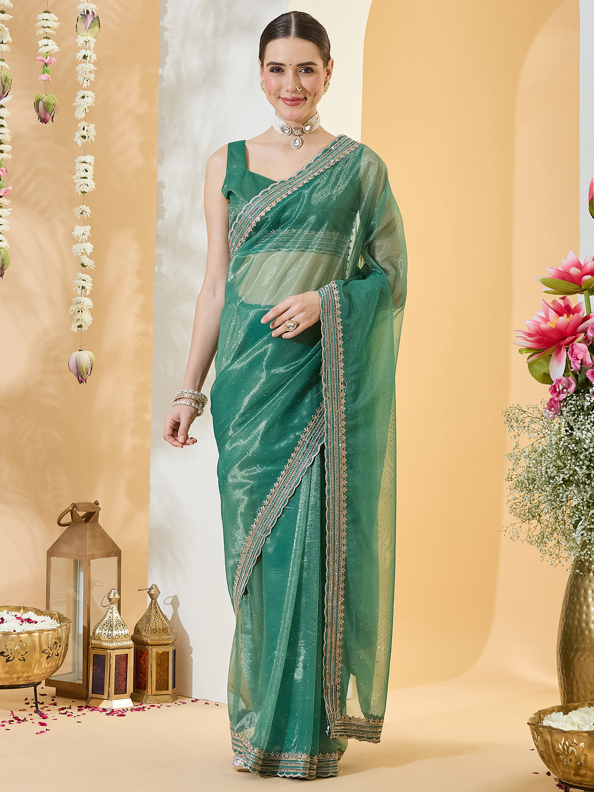 Woman wearing teal green net saree with ornamented surface design and teal green blouse