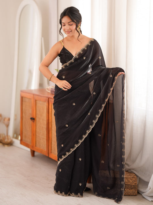 Woman wearing black satin saree with ornamented surface design and black blouse