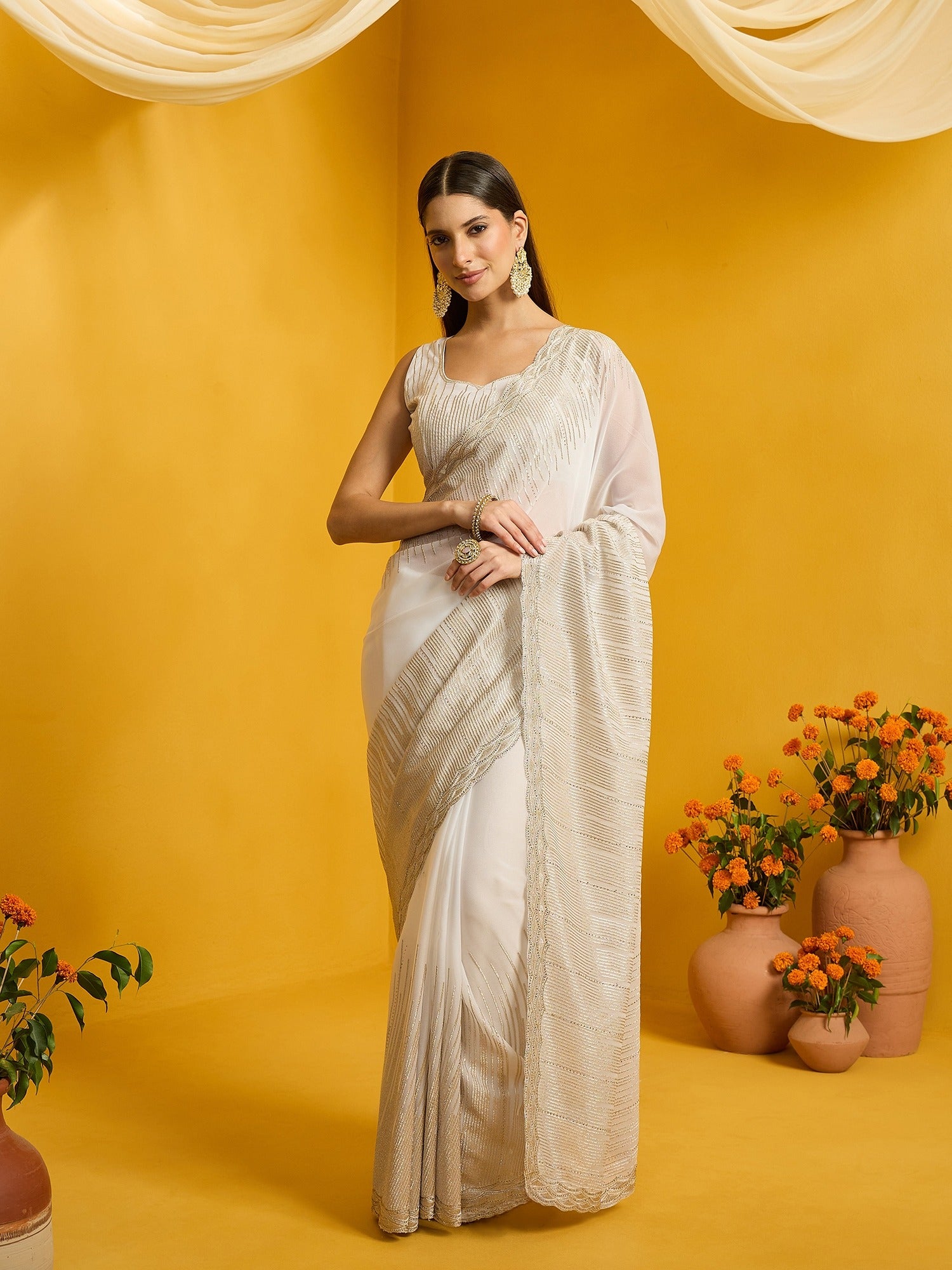 Woman wearing off white pure georgette saree with embroidered motif work and off white blouse