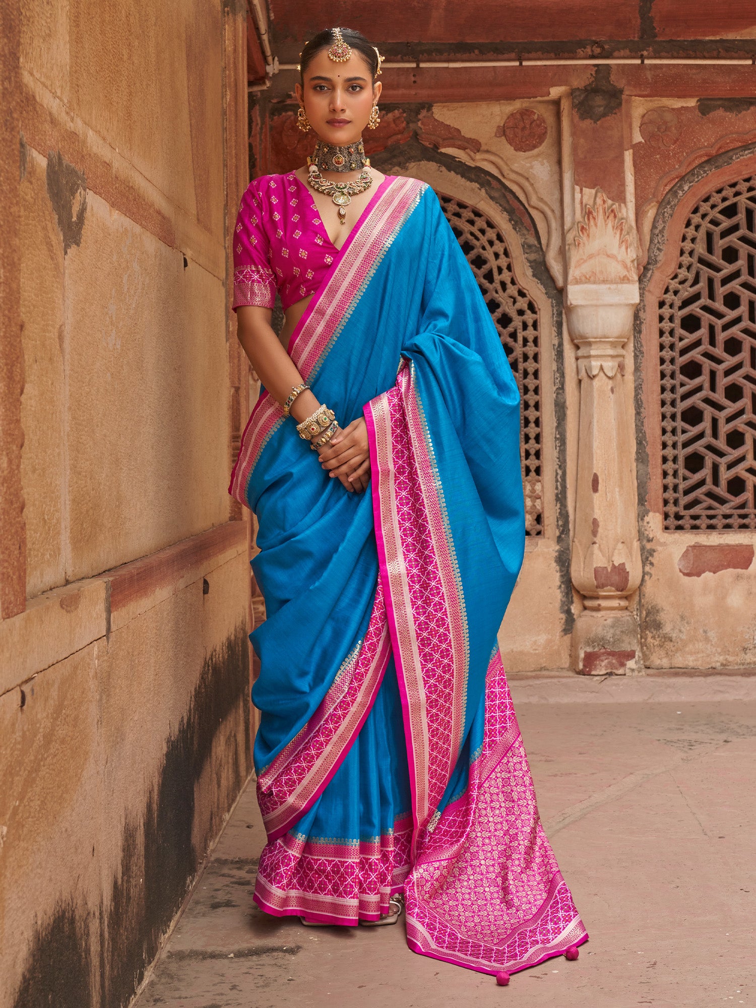 Woman wearing turquoise blue silk blend saree with clean solid-tone finish and pink blouse