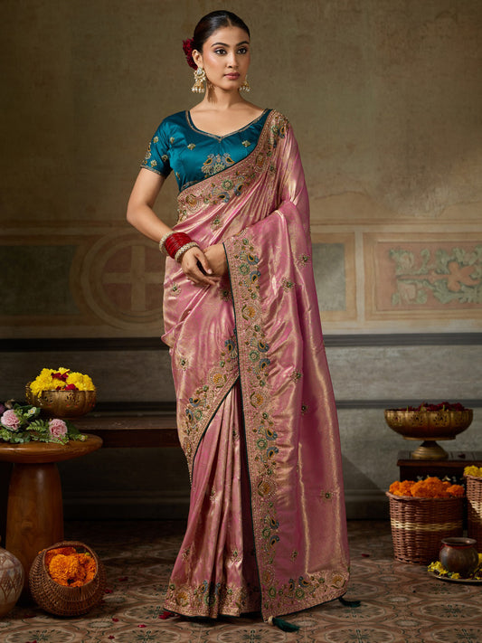 Woman wearing pink silk blend saree with ornamented surface design and teal blue blouse
