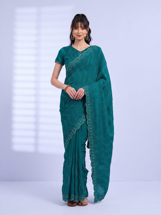 Woman wearing teal green tissue saree with geometric pattern design and teal green blouse