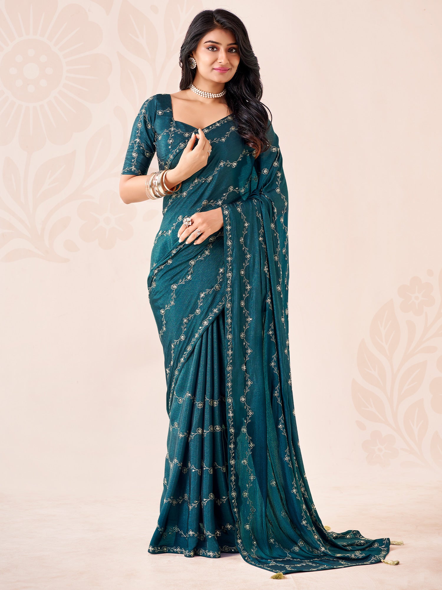 Woman wearing teal blue chiffon saree with ornamented surface design and teal blue blouse