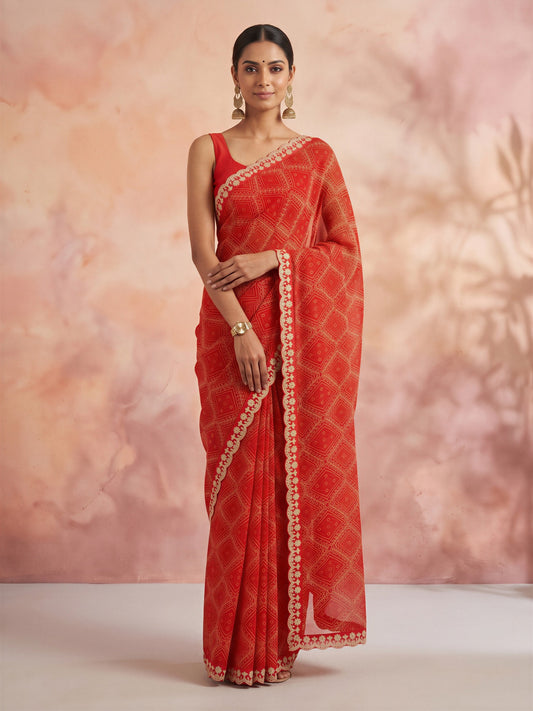 Woman wearing orange georgette saree with bandhani tie-dye dot work and orange blouse