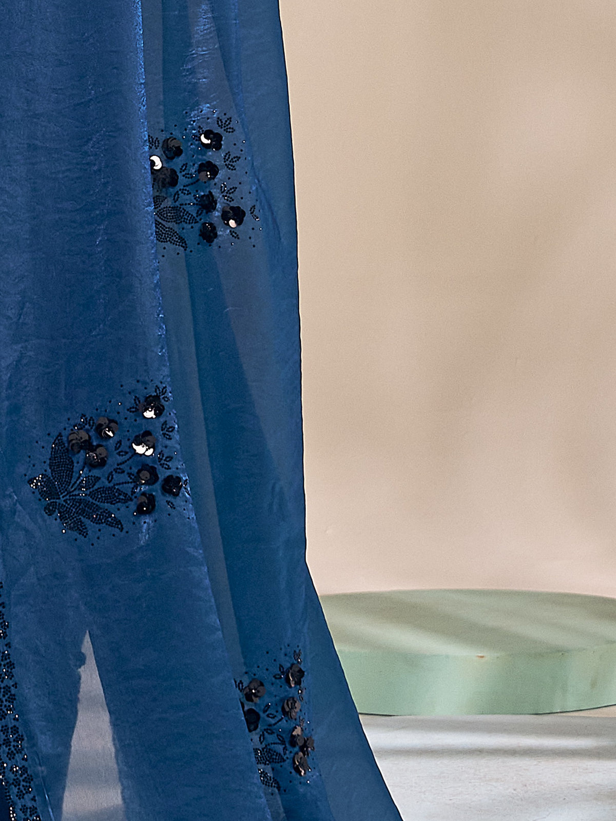 Pallu detail of teal blue satin silk saree showing ornamented surface design and scallop border